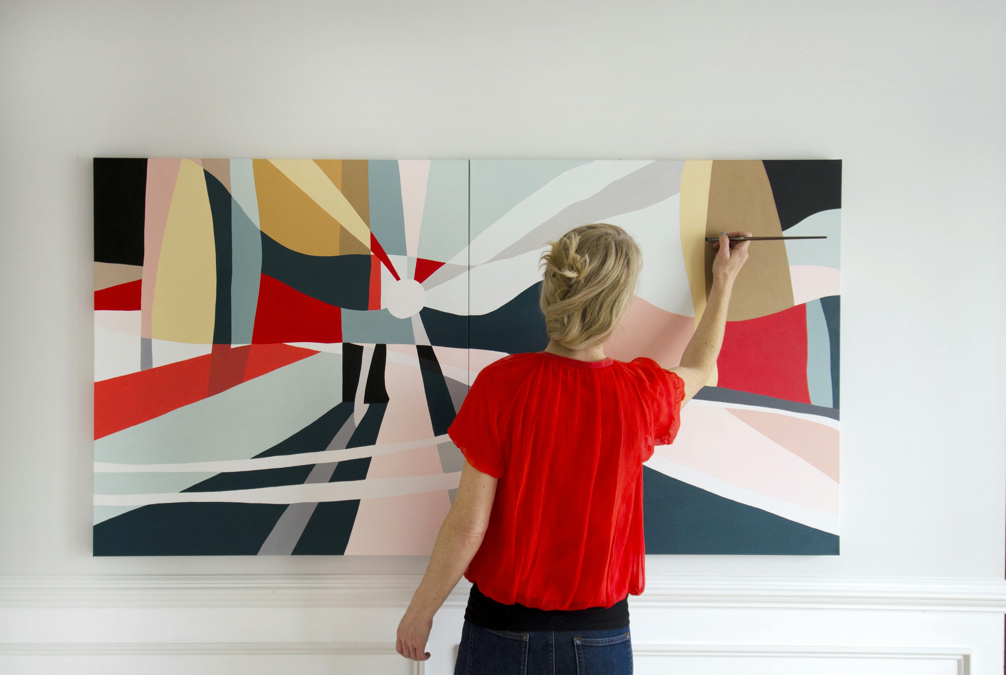 Artist Christina Flowers in a red shirt painting a large, abstract painting.