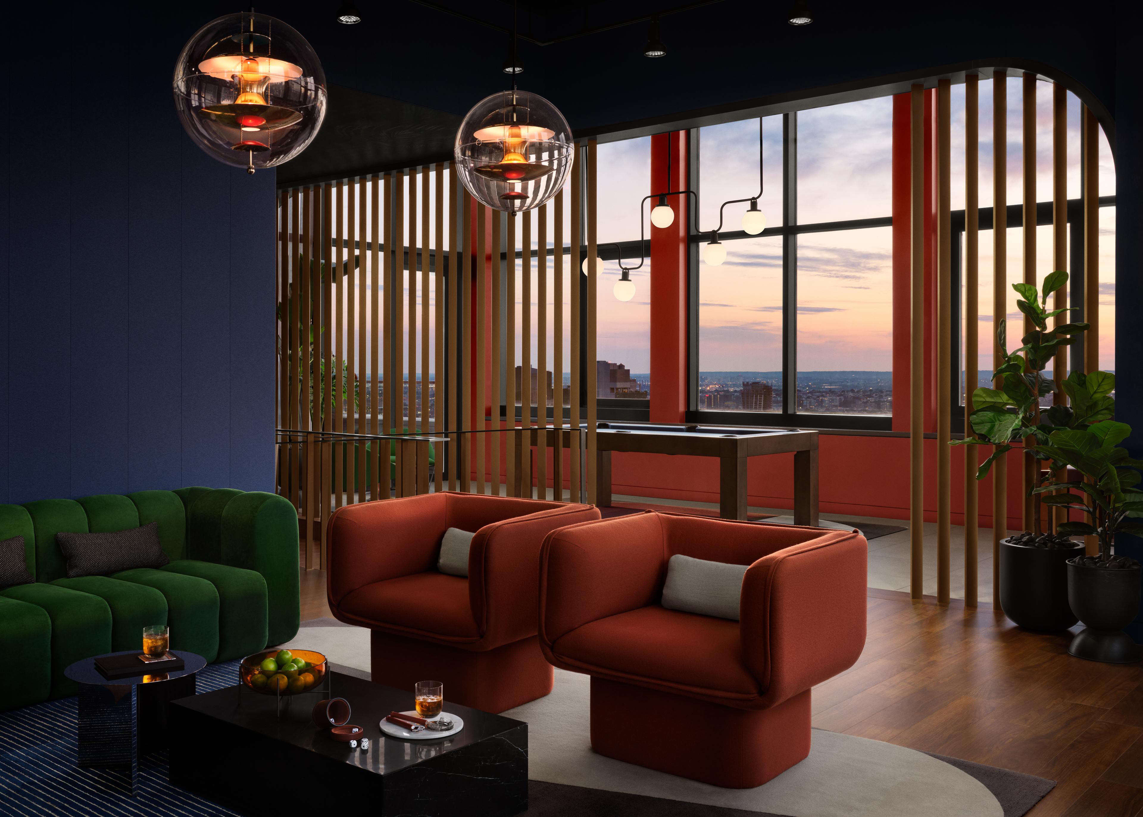 A rooftop lounge area at Anagram NoMad with orange armchairs and a view overlooking the Manhattan skyline at dusk.