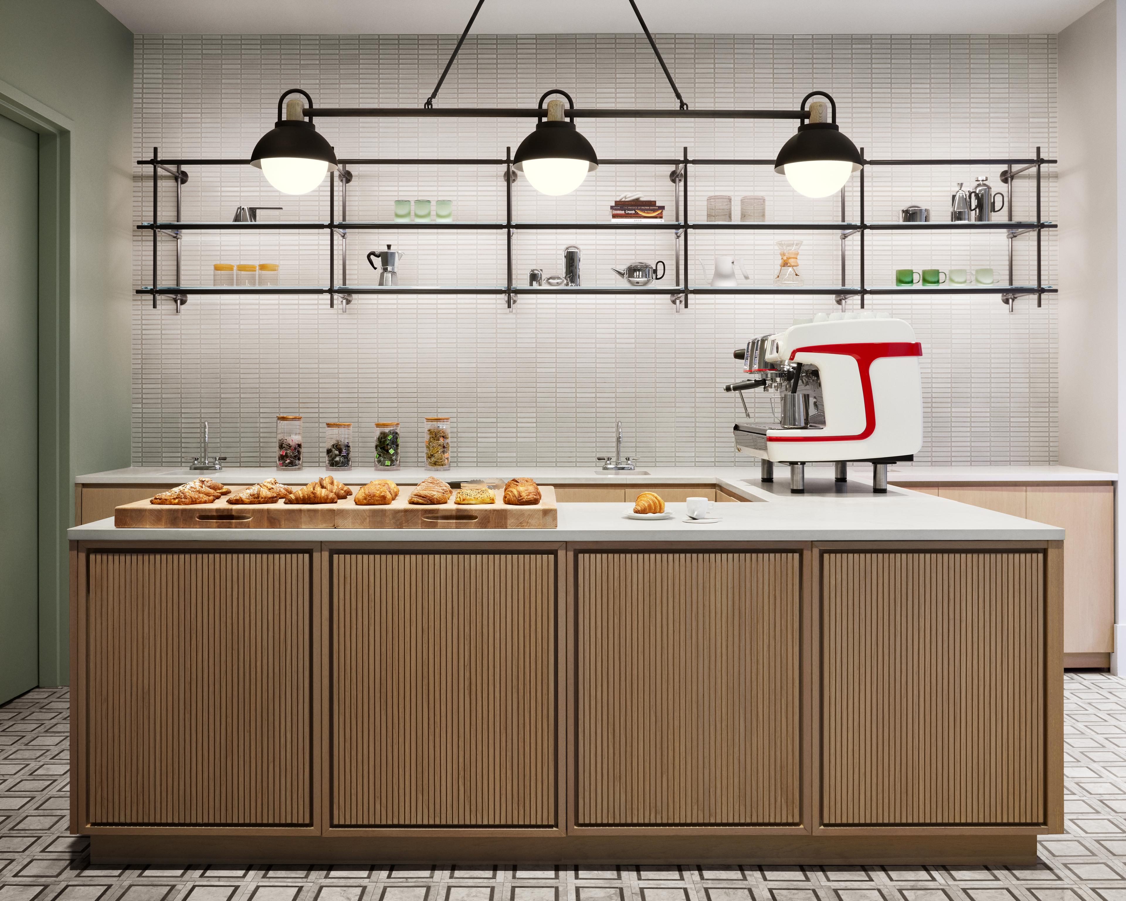 A kitchen with a large island, an assortment of pastries, and modern appliances within Anagram NoMad.