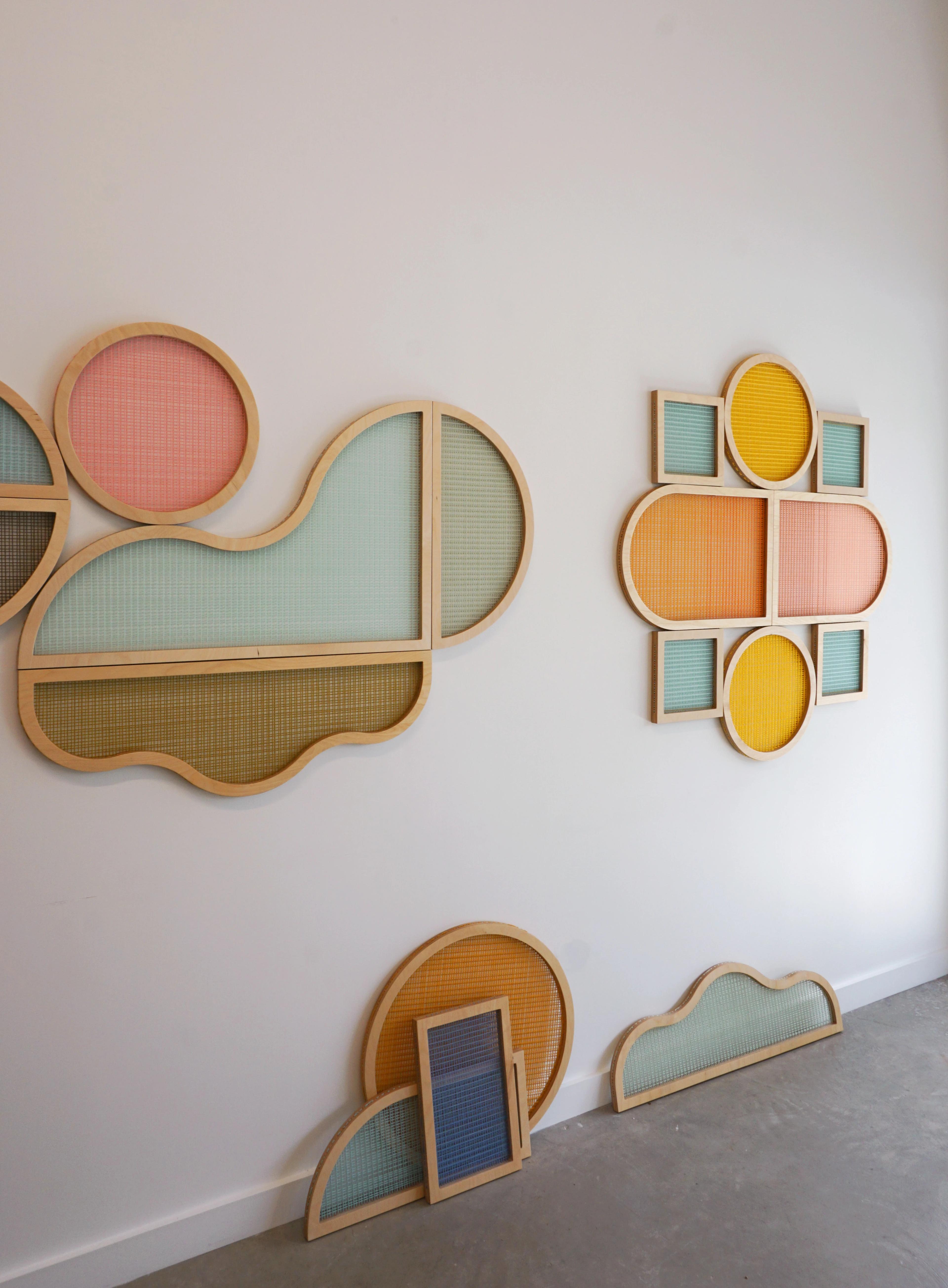 Textile shaped screens by artist Hayley Sheldon installed on a white wall in her studio.