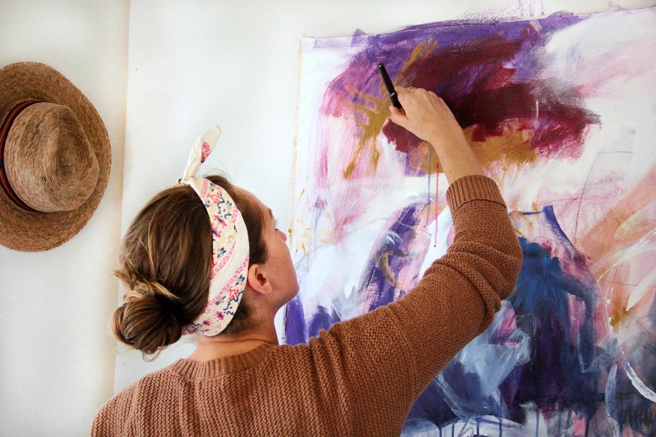 Elisa Gomez painting a colorful painting on canvas. 