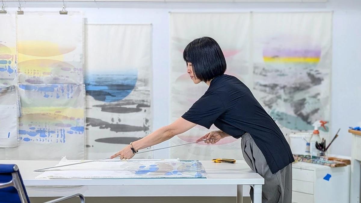 Artist Keiko Kamata measuring hand-pulled screenprints on fabric in her studio.