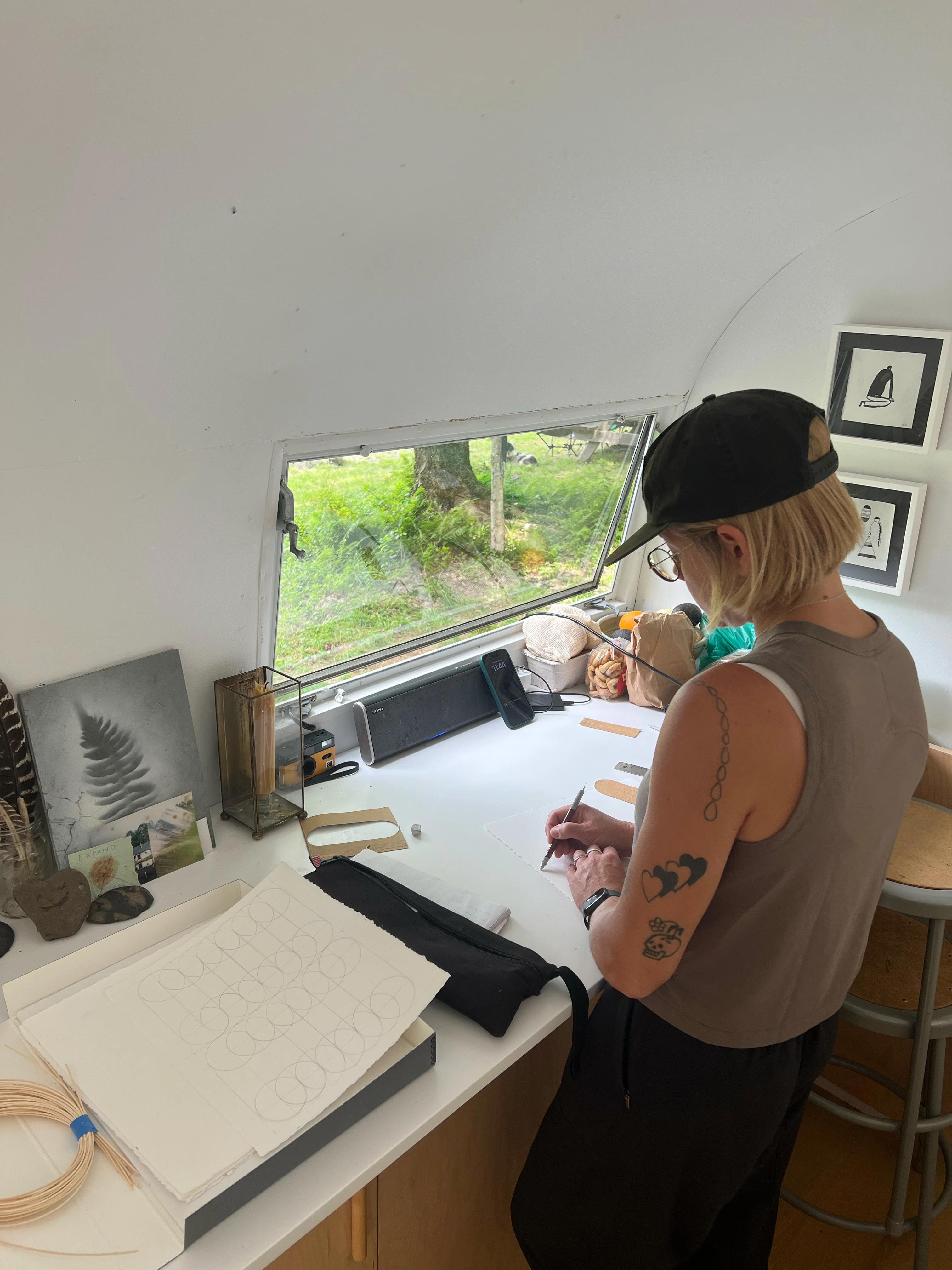 Artist Katrine Hildebrandt-Hussey drawing geometric lines on paper in her studio.