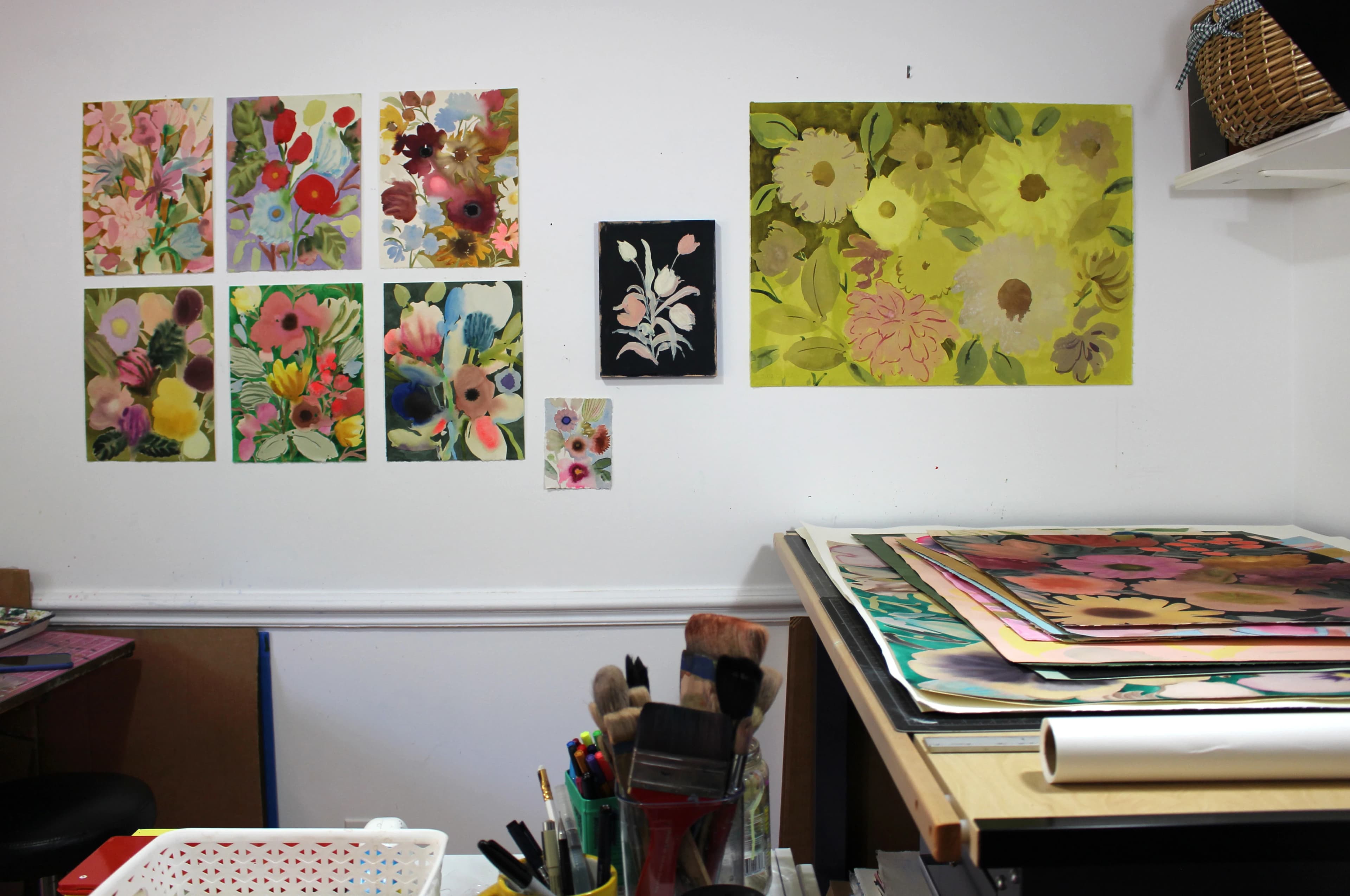 Various floral works installed on the white wall in artist Kayla Plosz Antiel's studio.