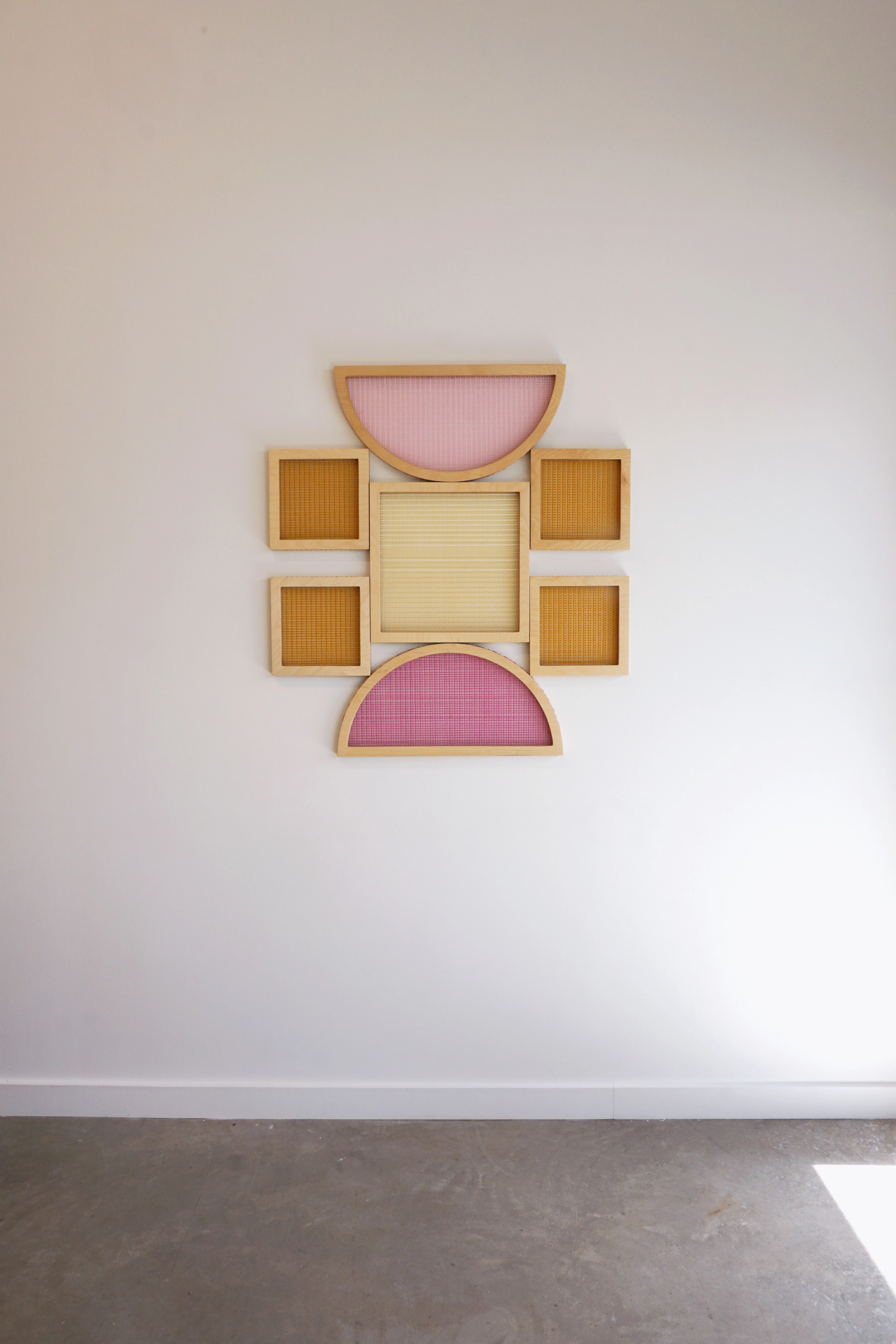 Pink and orange shaped screen composition by artist Hayley Sheldon installed on a white wall in her studio.