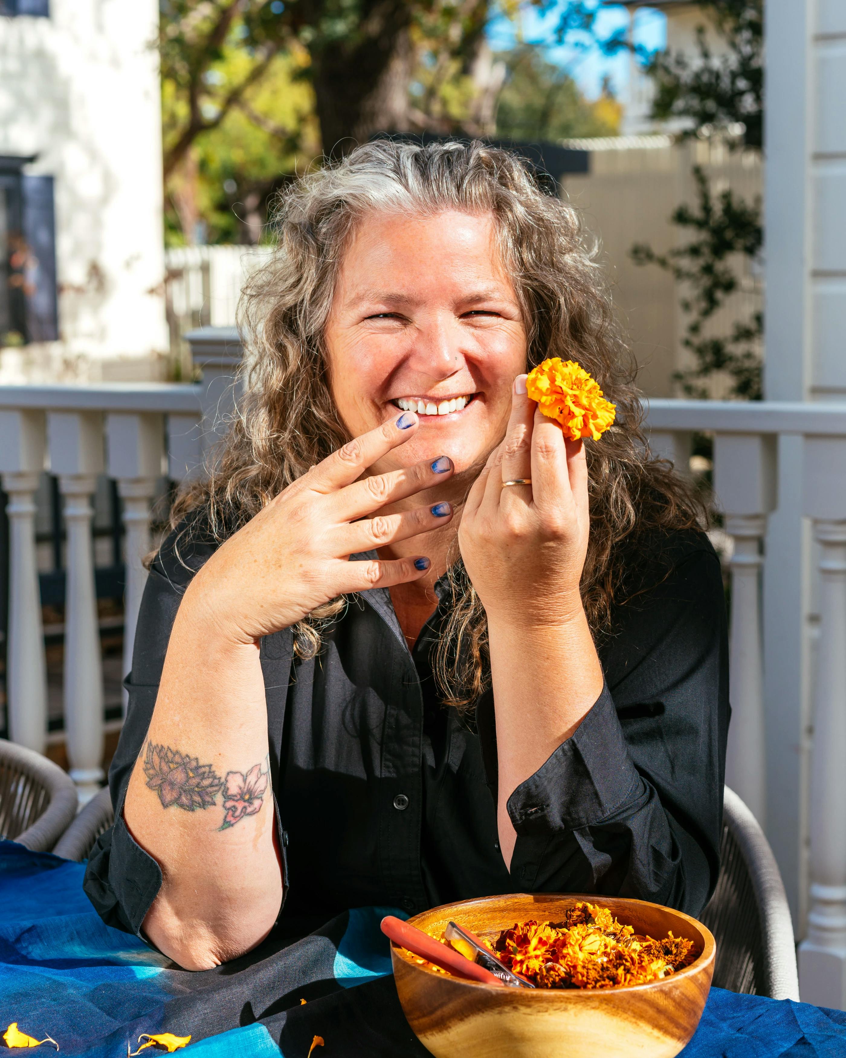 Artist Carrie Crawford holding a orange marigold flowers.