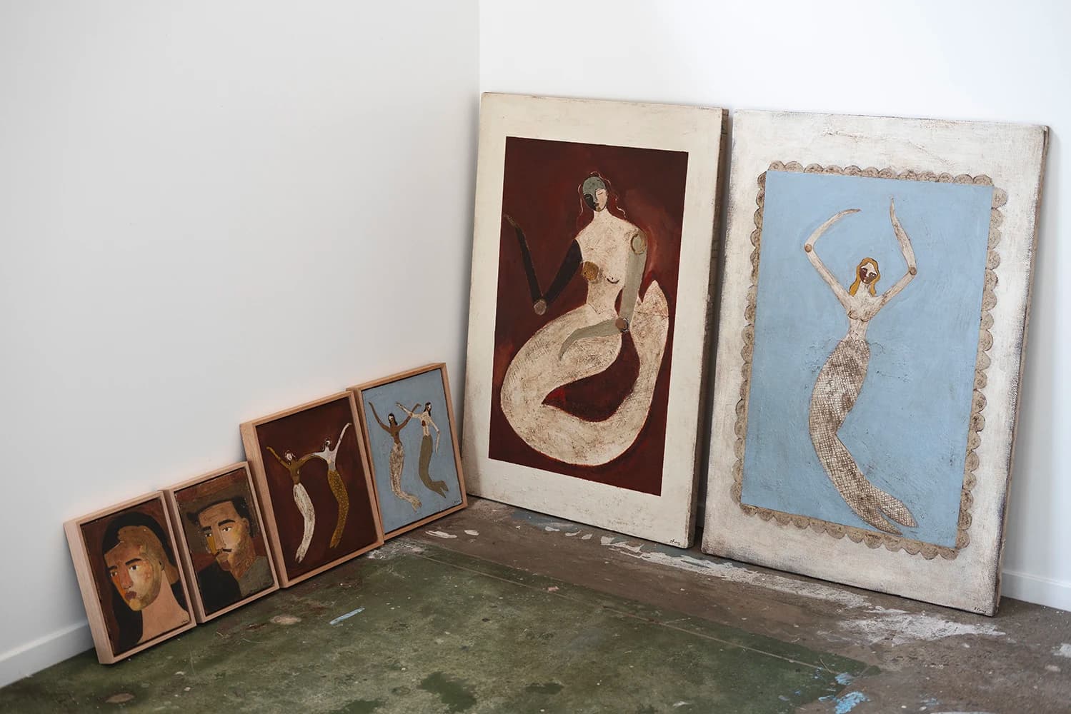 Paintings of various sizes with portraits, mermaids, and images from mythology by artist Brittany Ferns in her studio.