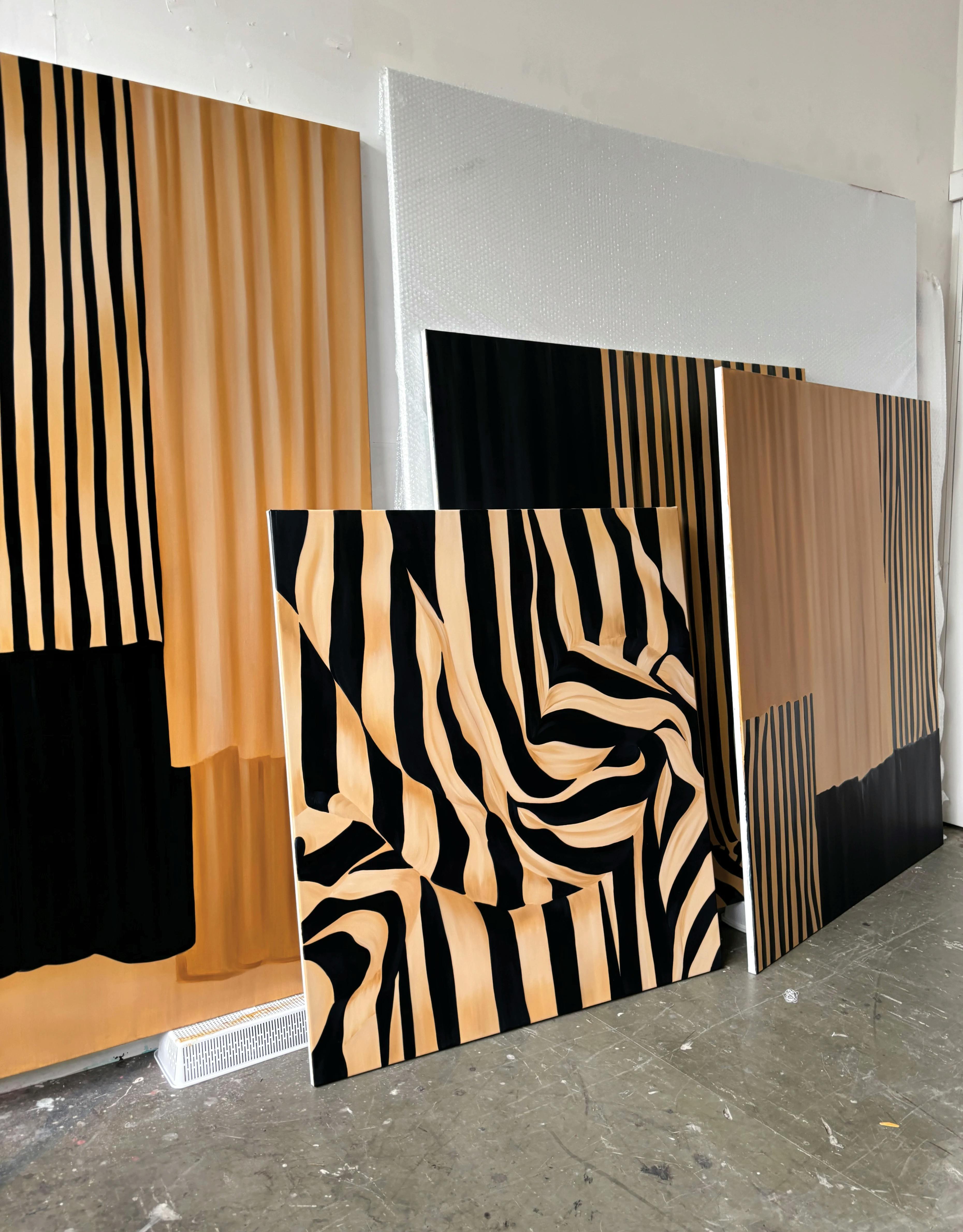 Oversized, striped gold and black paintings on canvas by artist Caroline Walls.