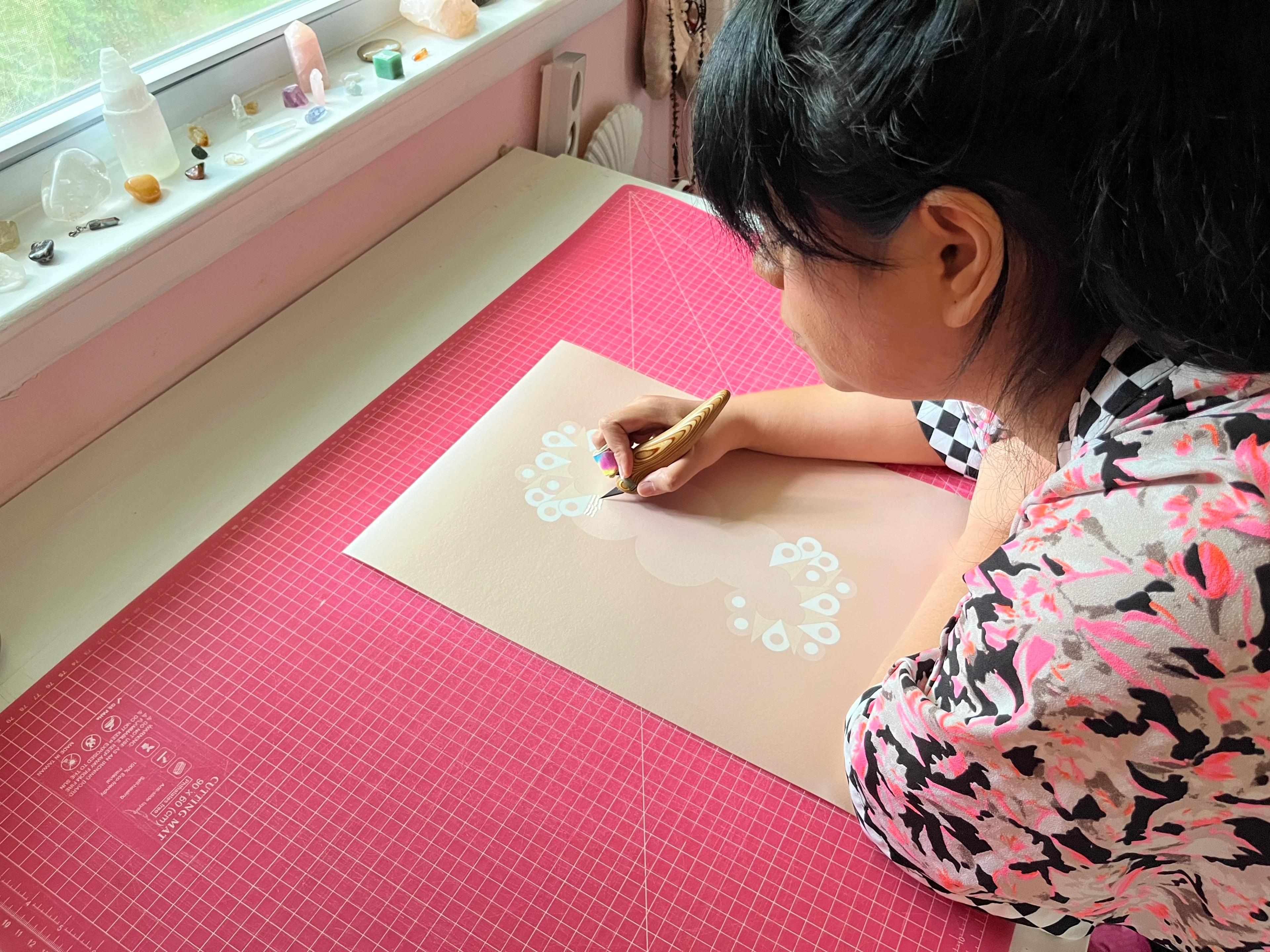 Artist Lucha Rodríguez working on a knife-cut drawing in her studio.