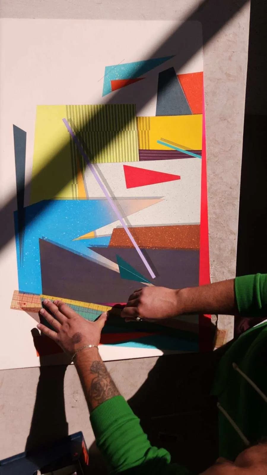 Artist Michael Moncibaiz using a ruler to create straight edges on his abstract, geometric work.