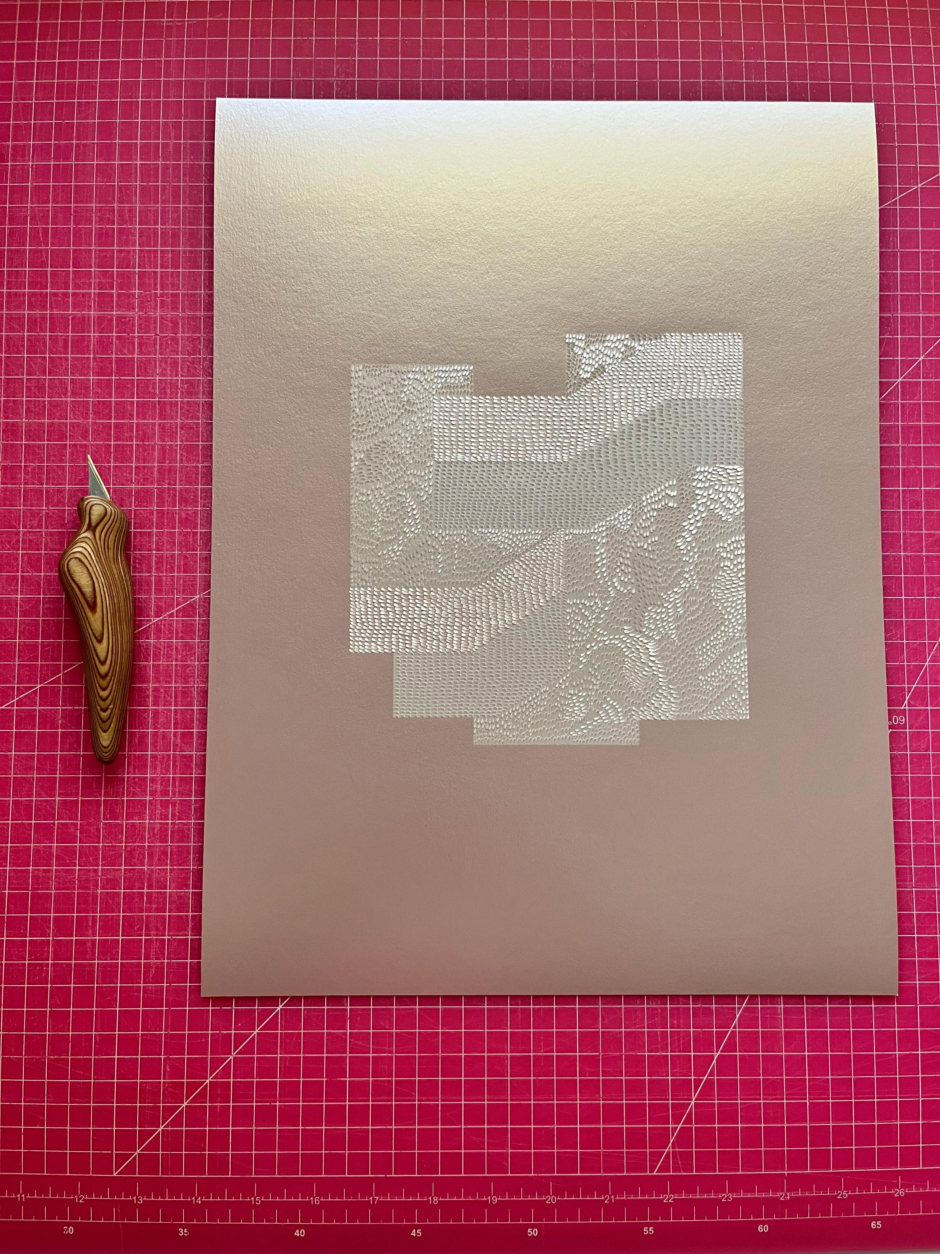 A shimmery knife-cut drawing by artist Lucha Rodríguez on a pink grid mat in her studio.