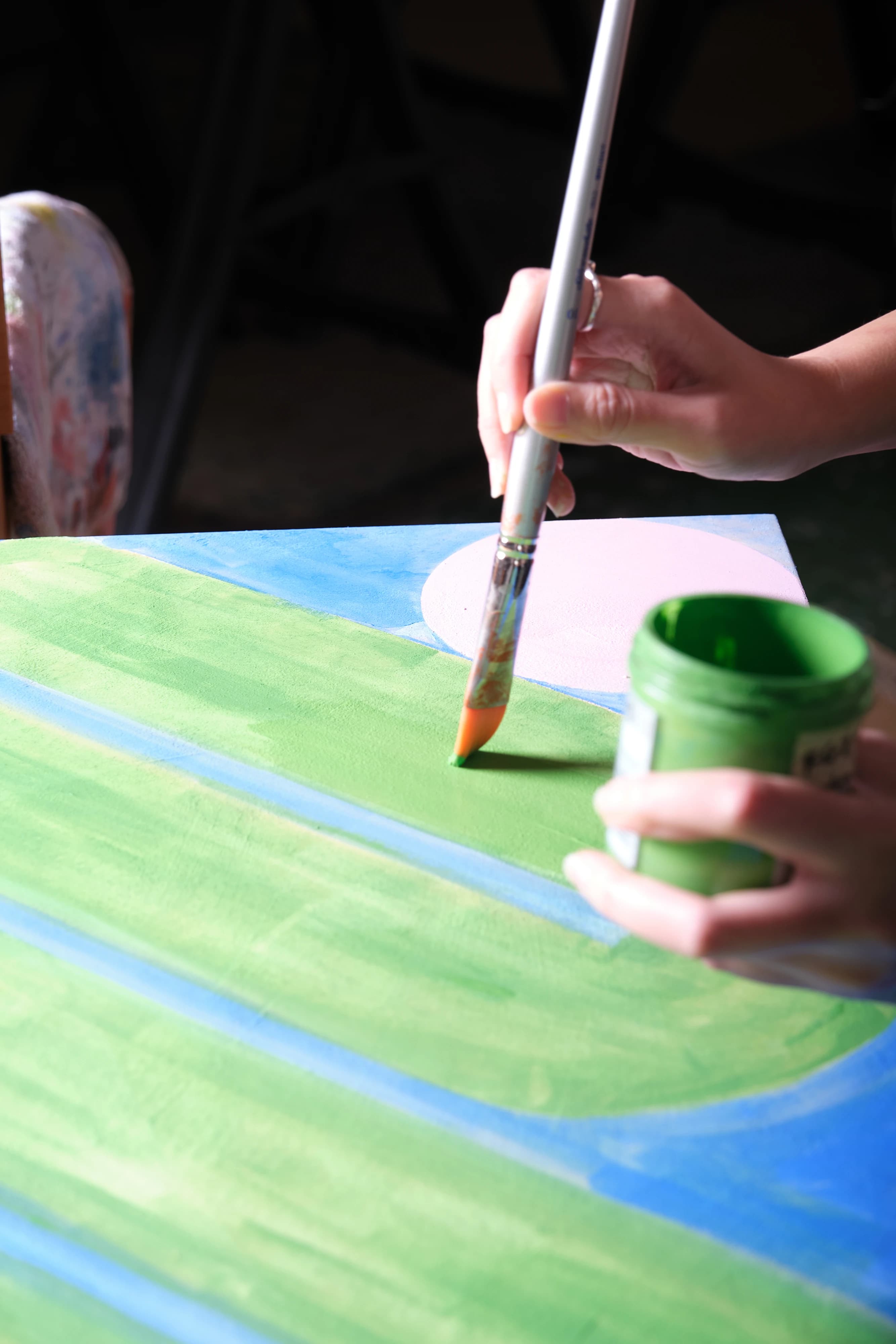 A close-up of artist Evi O. painting green lines on canvas.