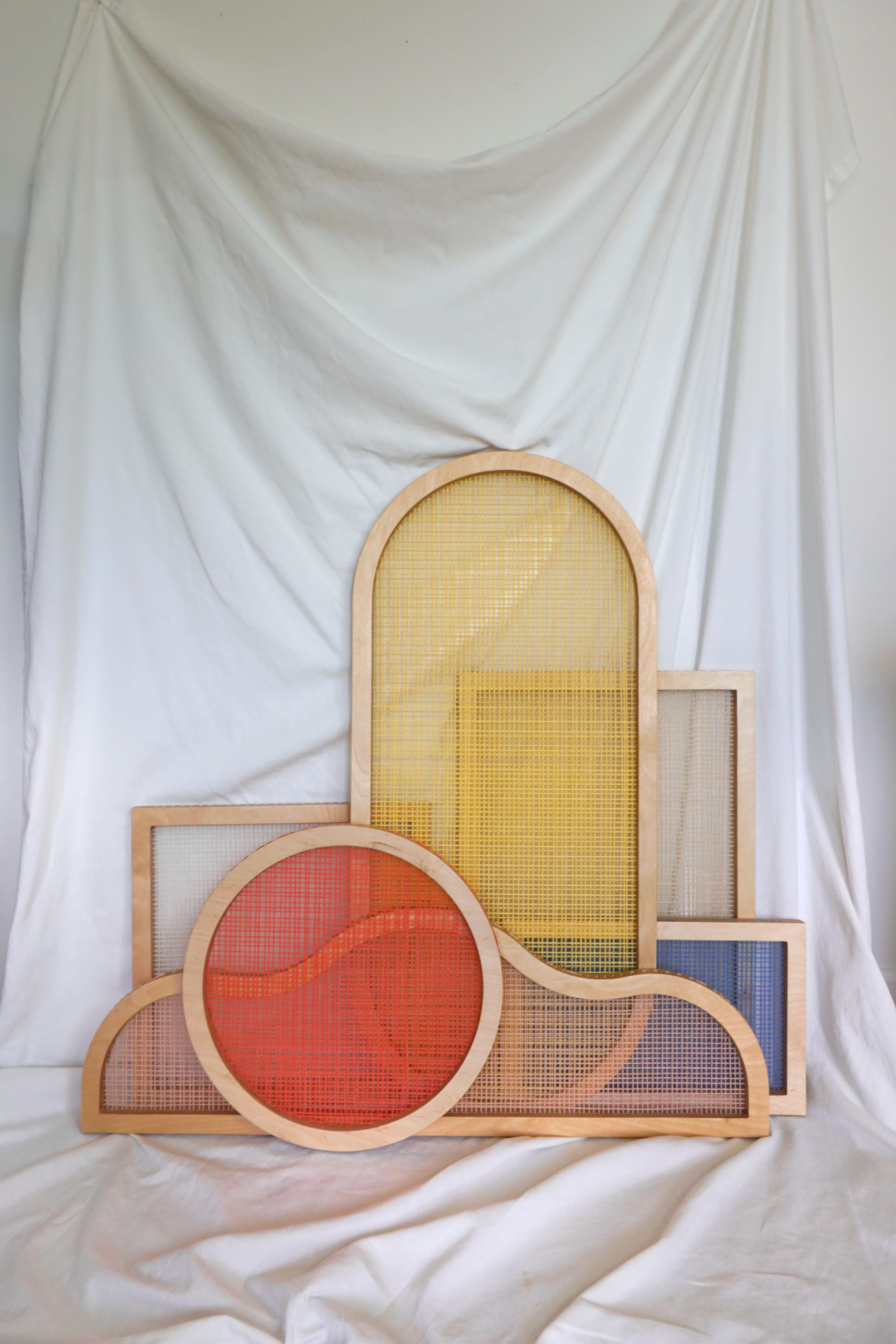 Colorful shaped screens by artist Hayley Sheldon against white fabric in her studio.