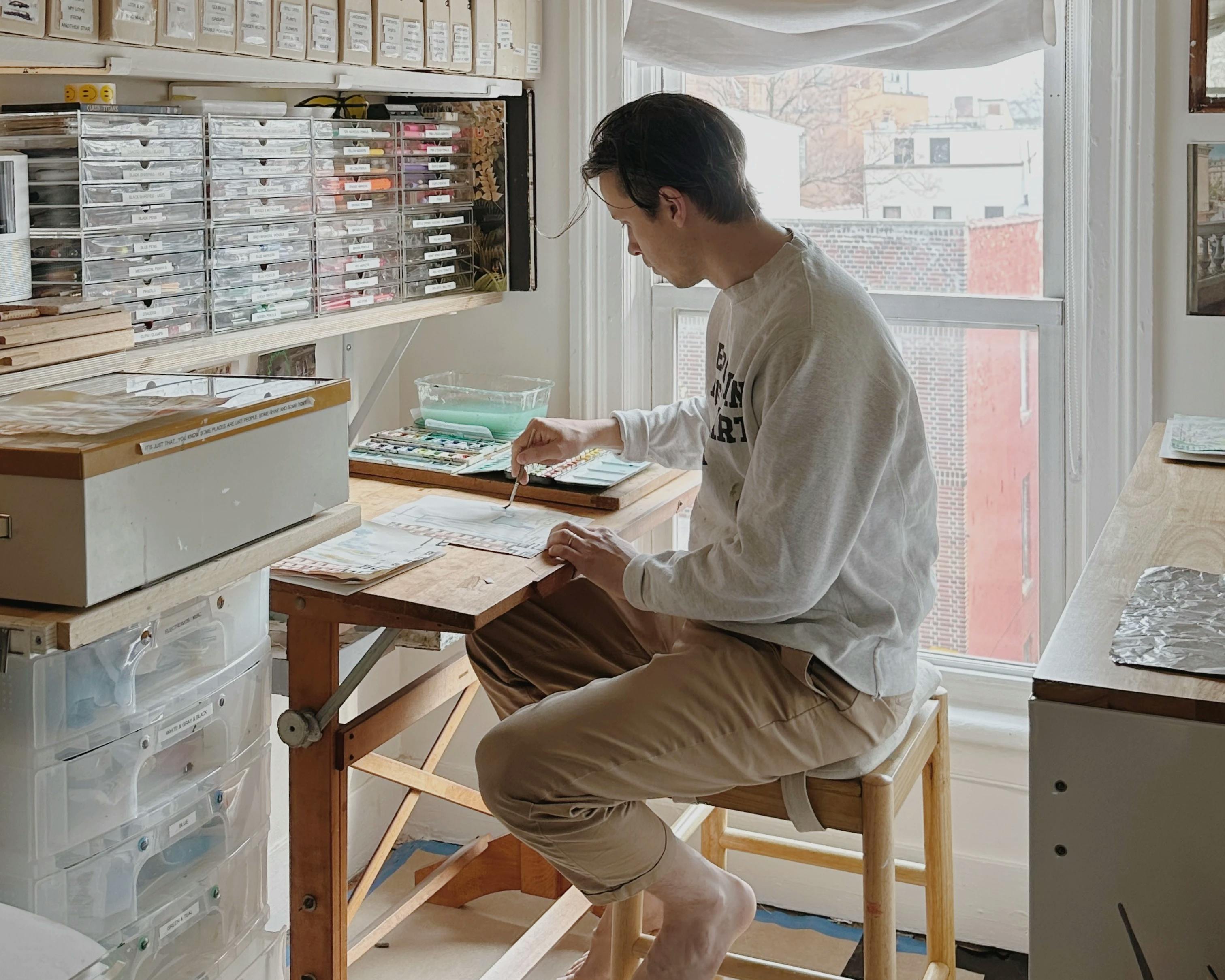 Artist David Rhoads working on a watercolor painting in his small, but organized Brooklyn studio.