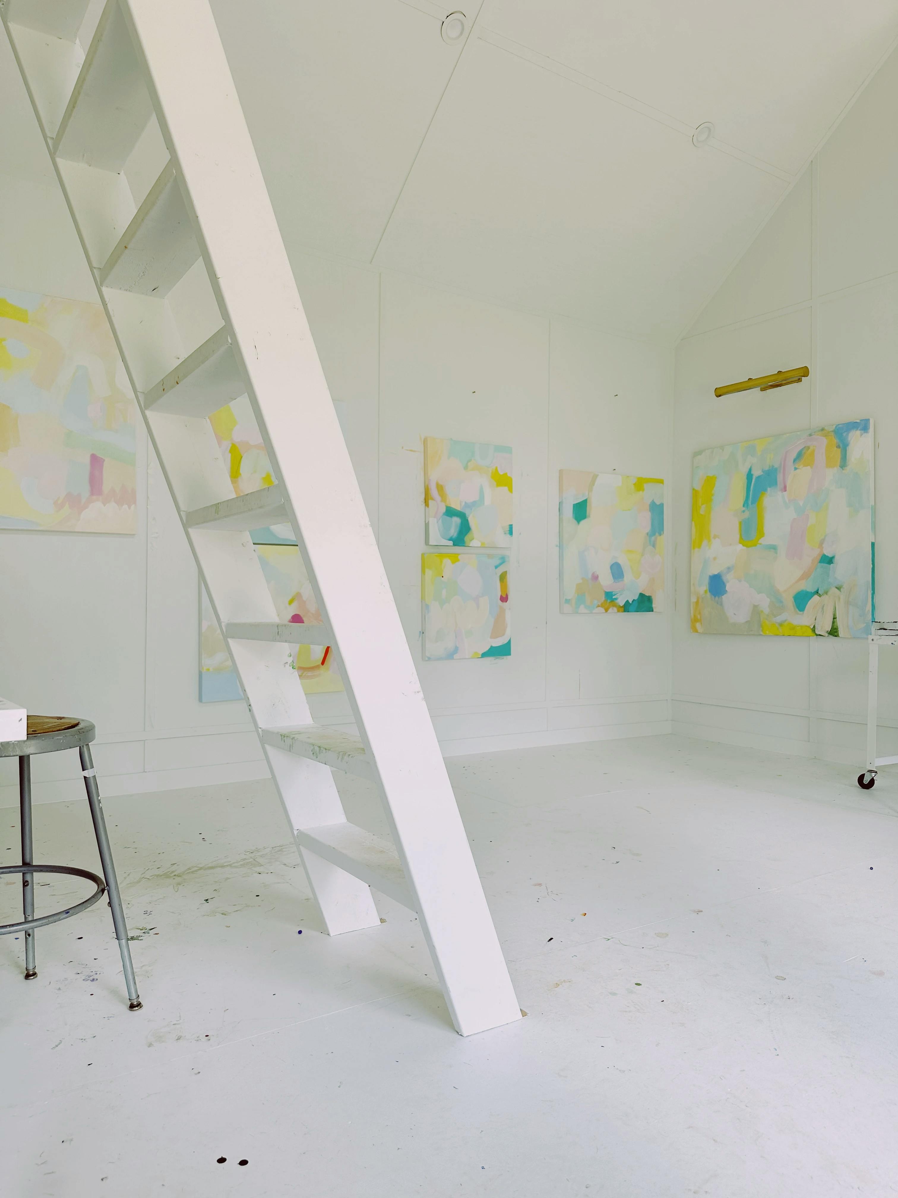 Abstract paintings by artist Britt Bass within a studio with a large white ladder.