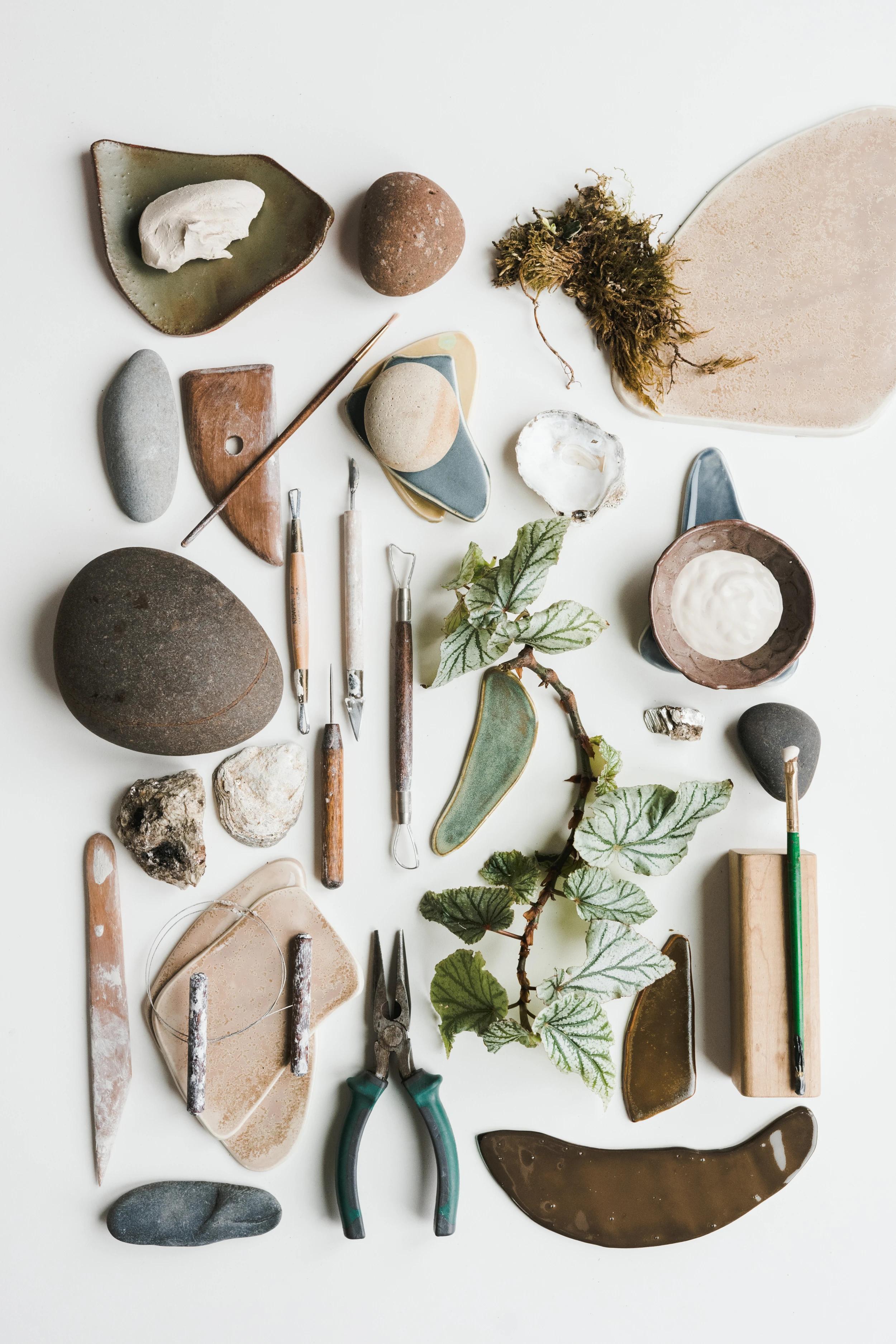 An assembly of tools, paint, and natural materials like rocks and plants in artist Christina Watka's studio.