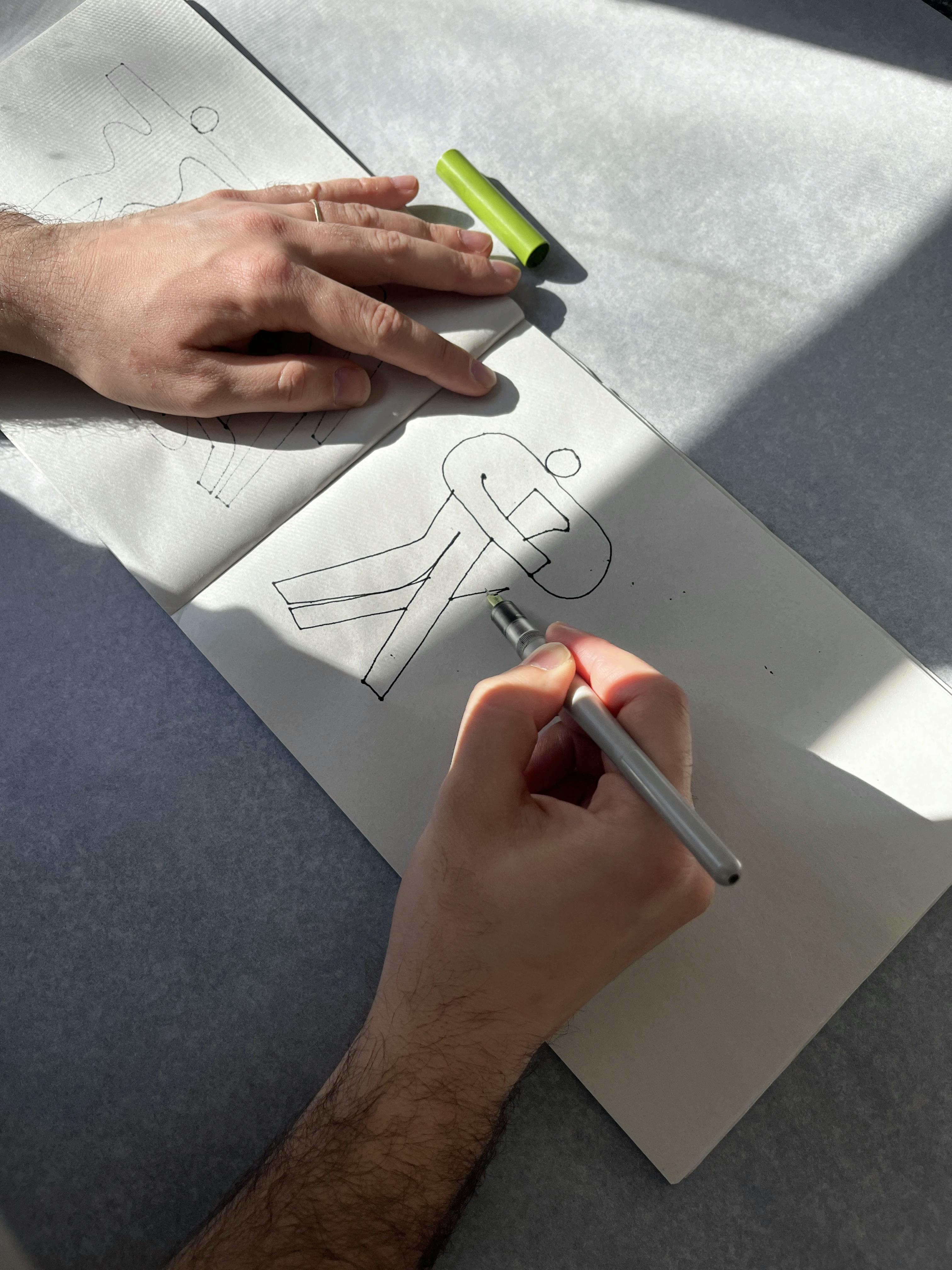 Artist Lourenço Providência sketching abstract, figurative shapes in a notepad.