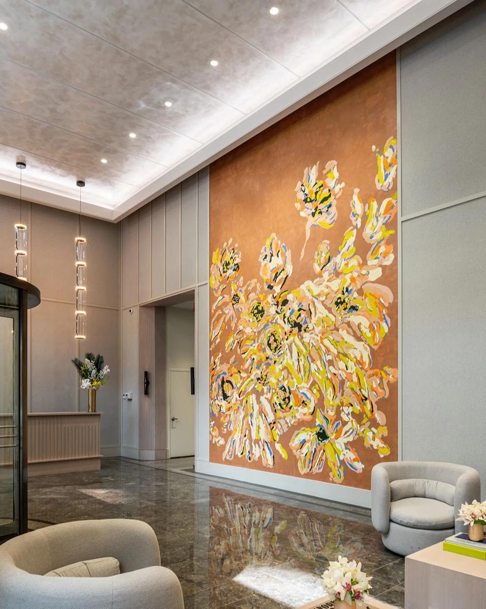 A large brown, yellow, and white floral mural by Erin Lynn Welsh flanked by two leather chairs in the lobby of Anagram NoMad.