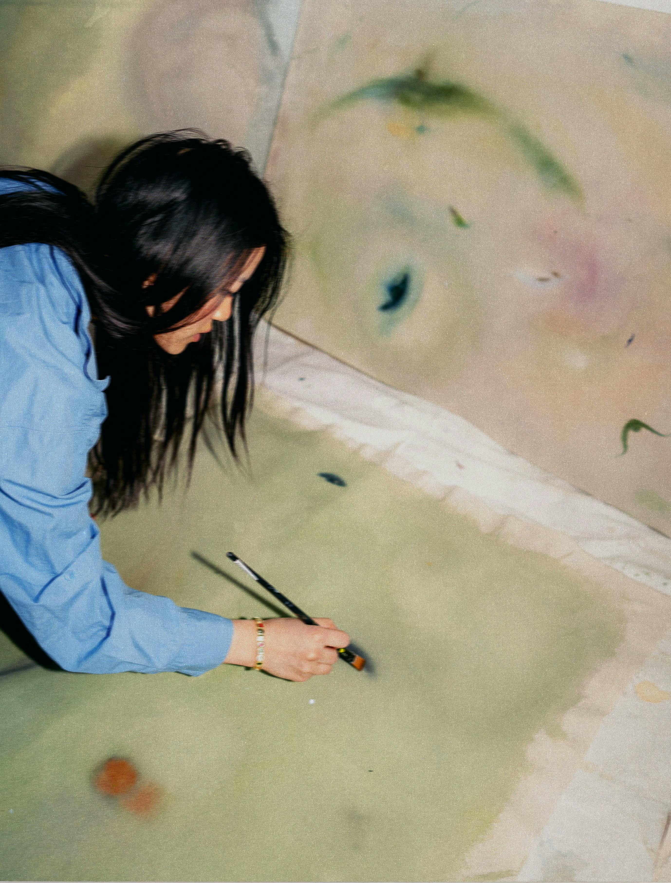 Artist Arlina Cai painting soft abstract works in her studio.