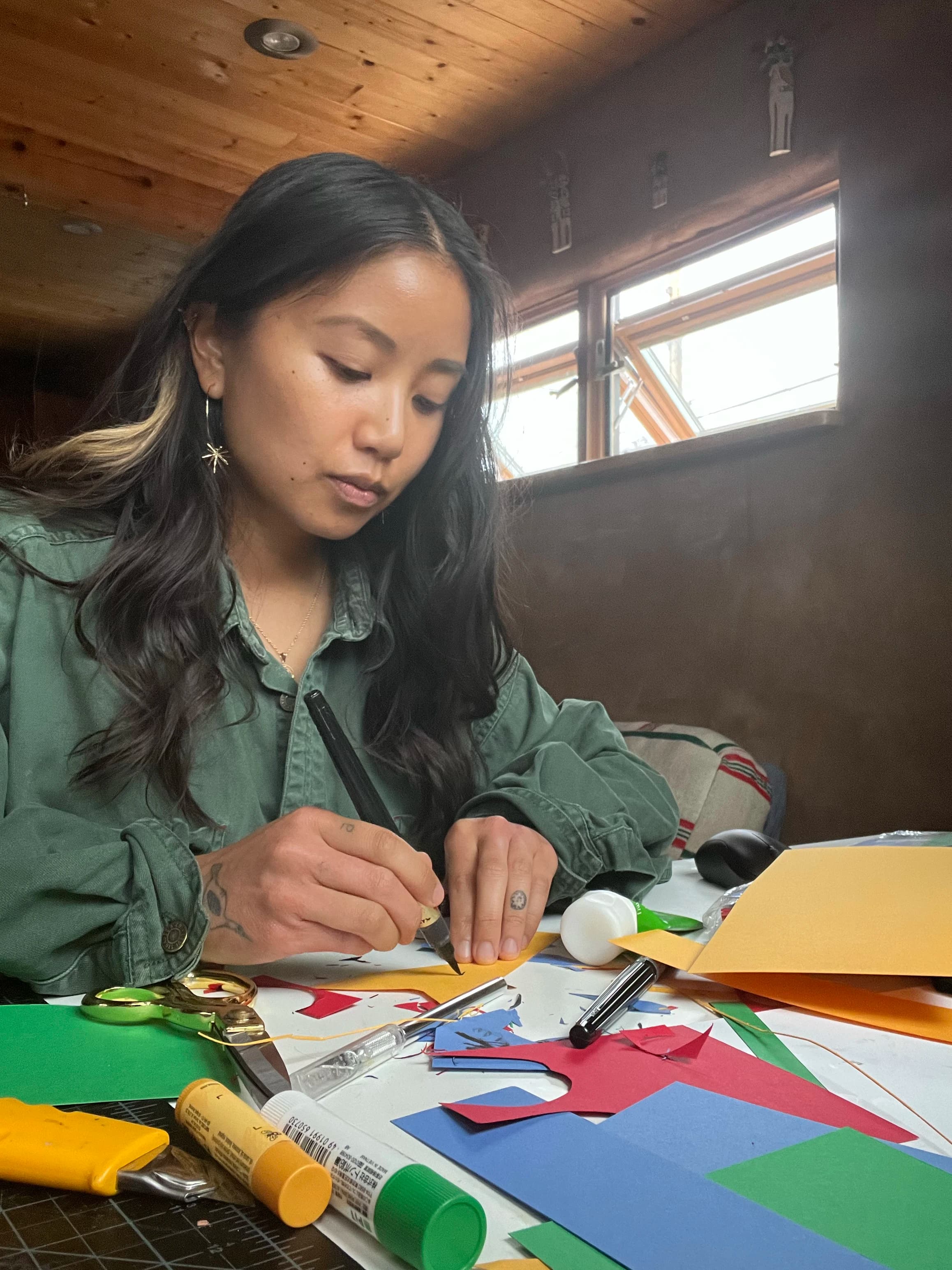 Artist Paulina Ho working with colorful scraps of paper in her studio.