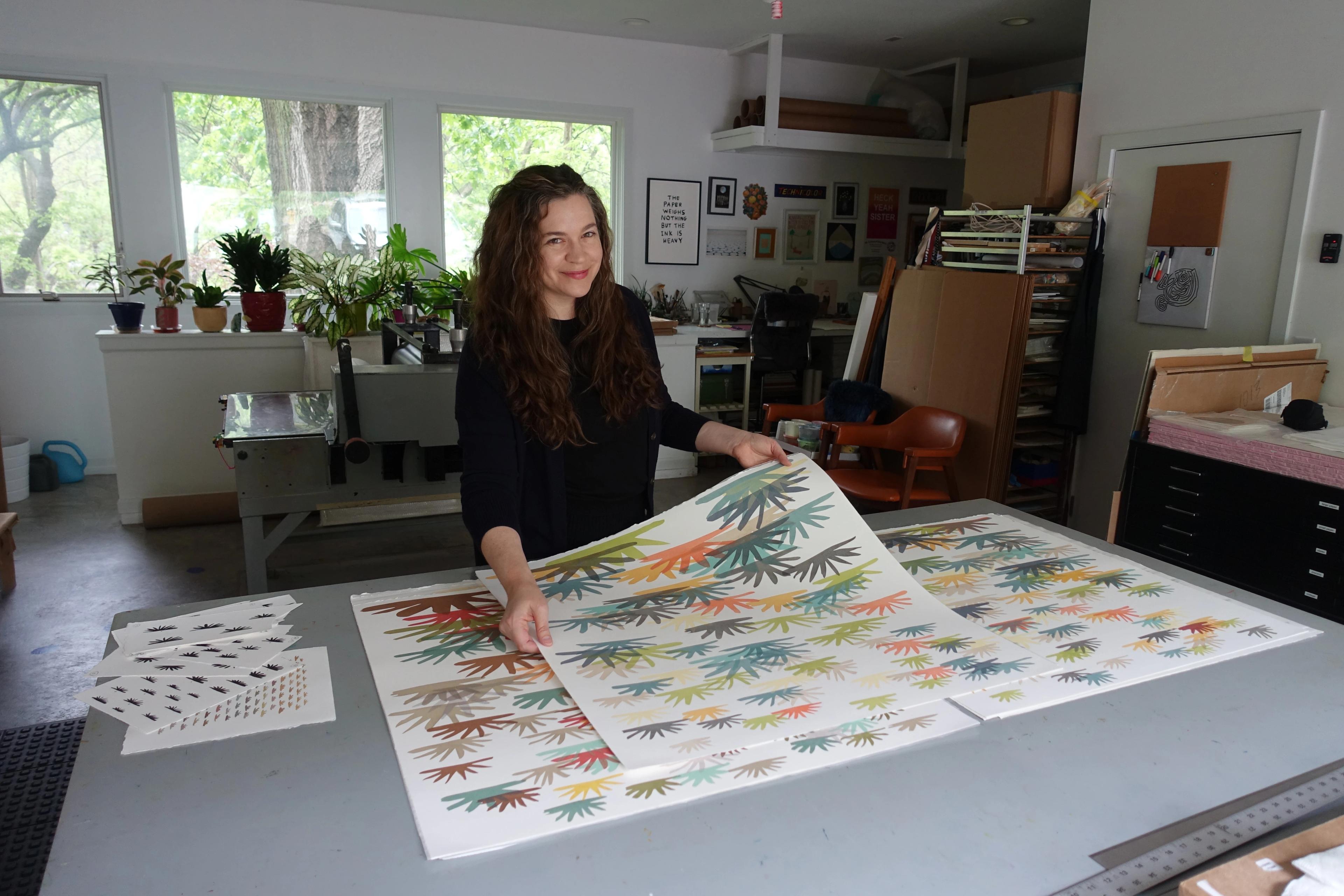 Laura Berman holding prints in her studio.