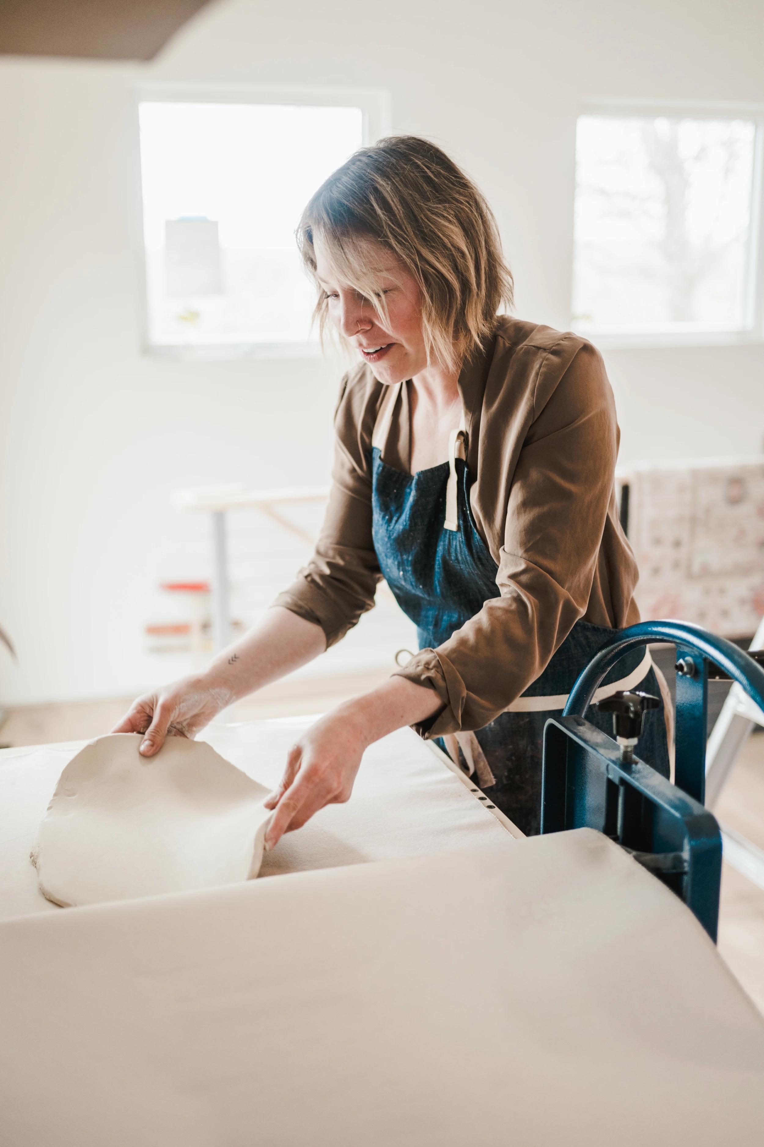 Artist Christina Watka creating a flattened clay disc inside her Maine studio.