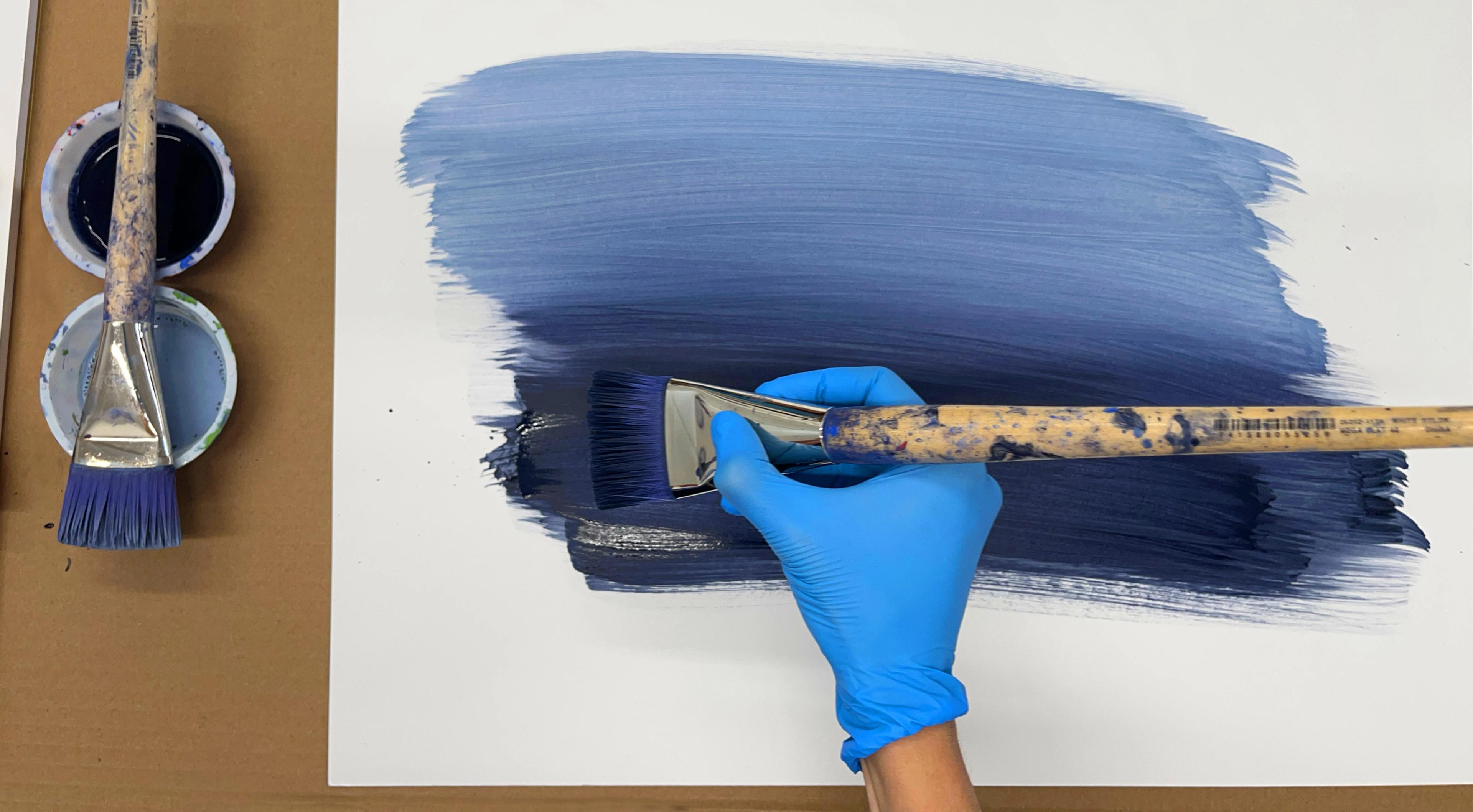 Artist Senem Oezdogan painting blue brushstrokes on paper in her studio.