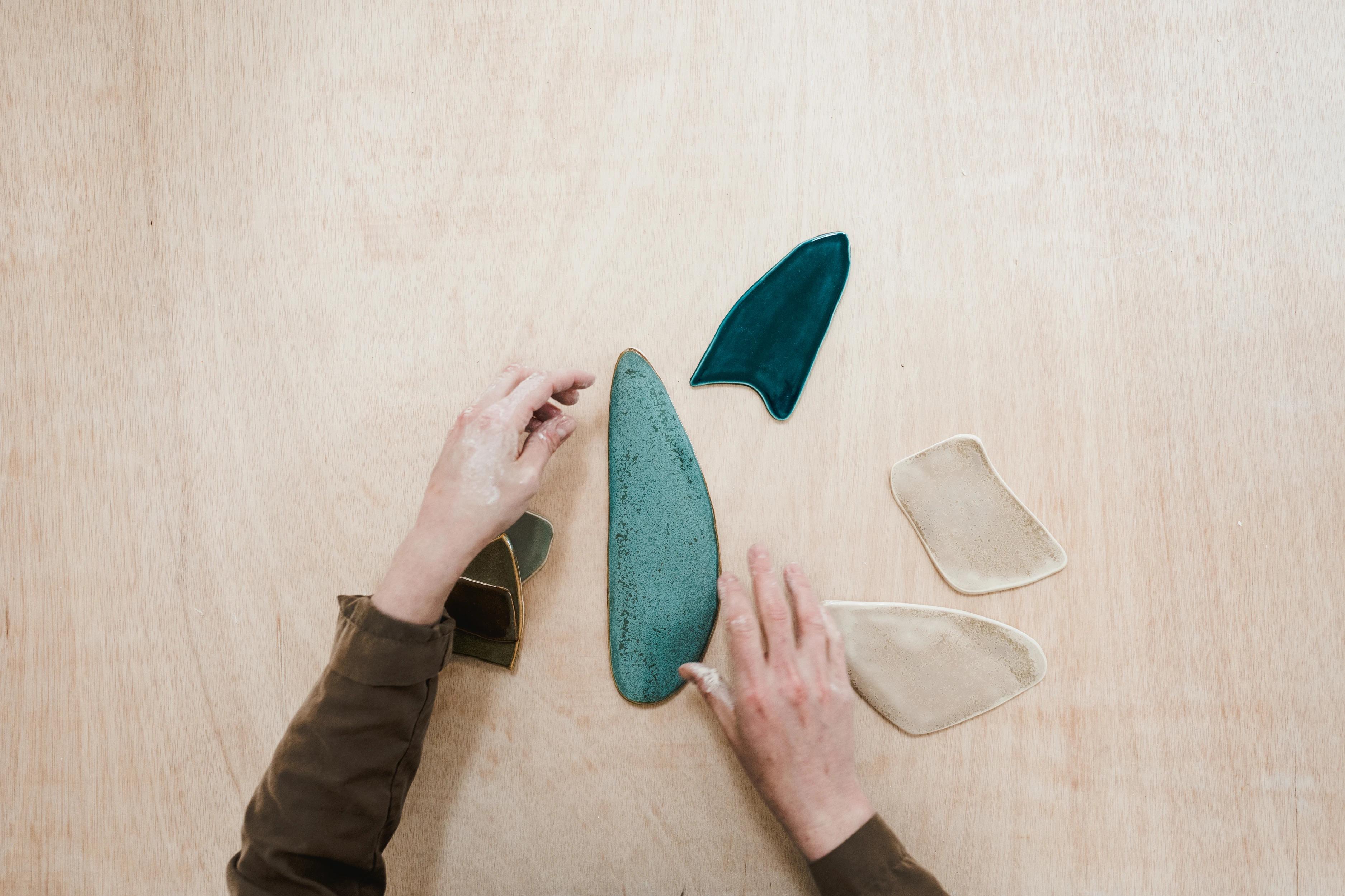 Artist Christina Watka working on teal, blue, and beige porcelain pieces in her studio.