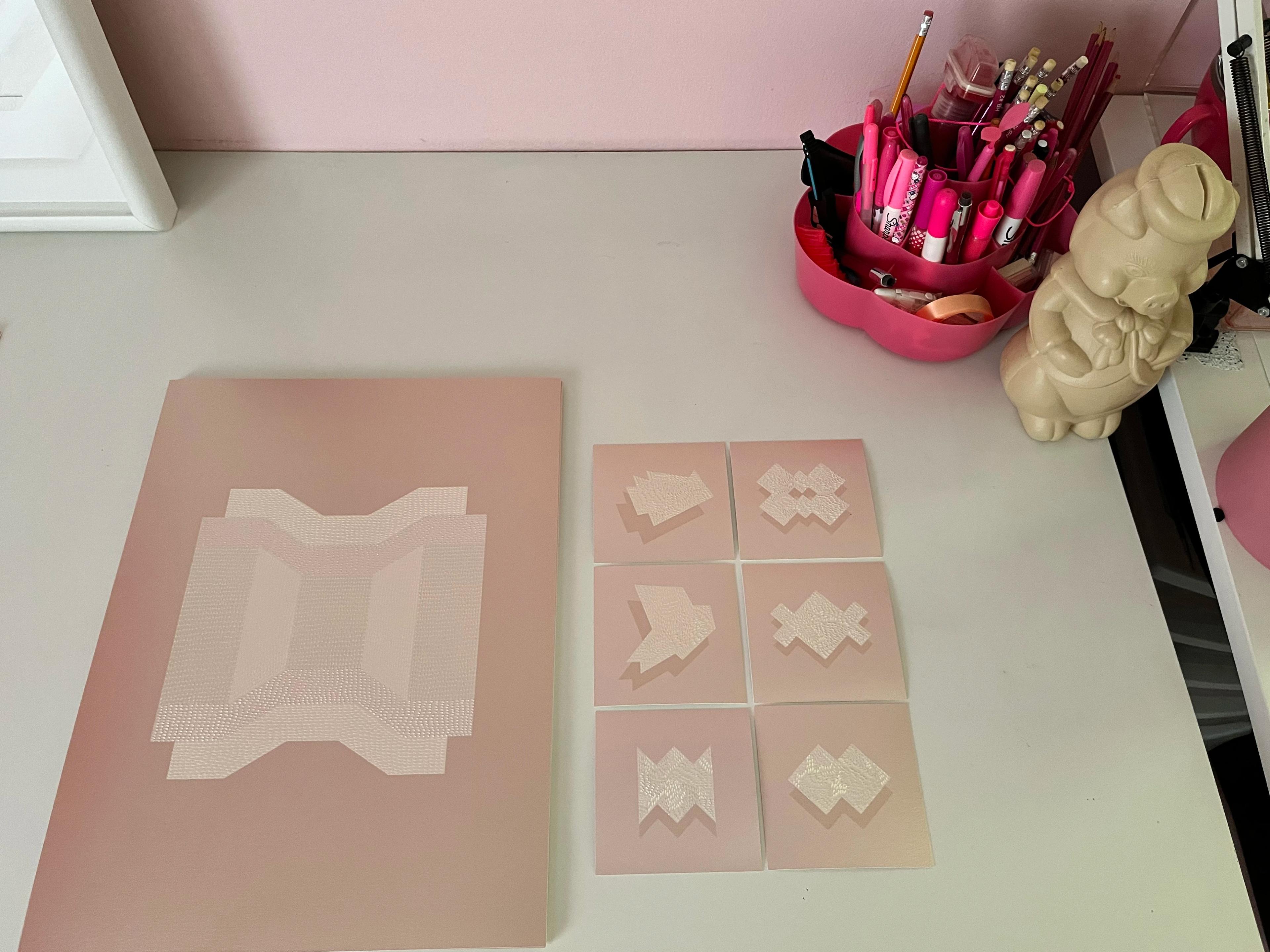 Seven pink knife-cut drawings by artist Lucha Rodríguez on a table in her studio.