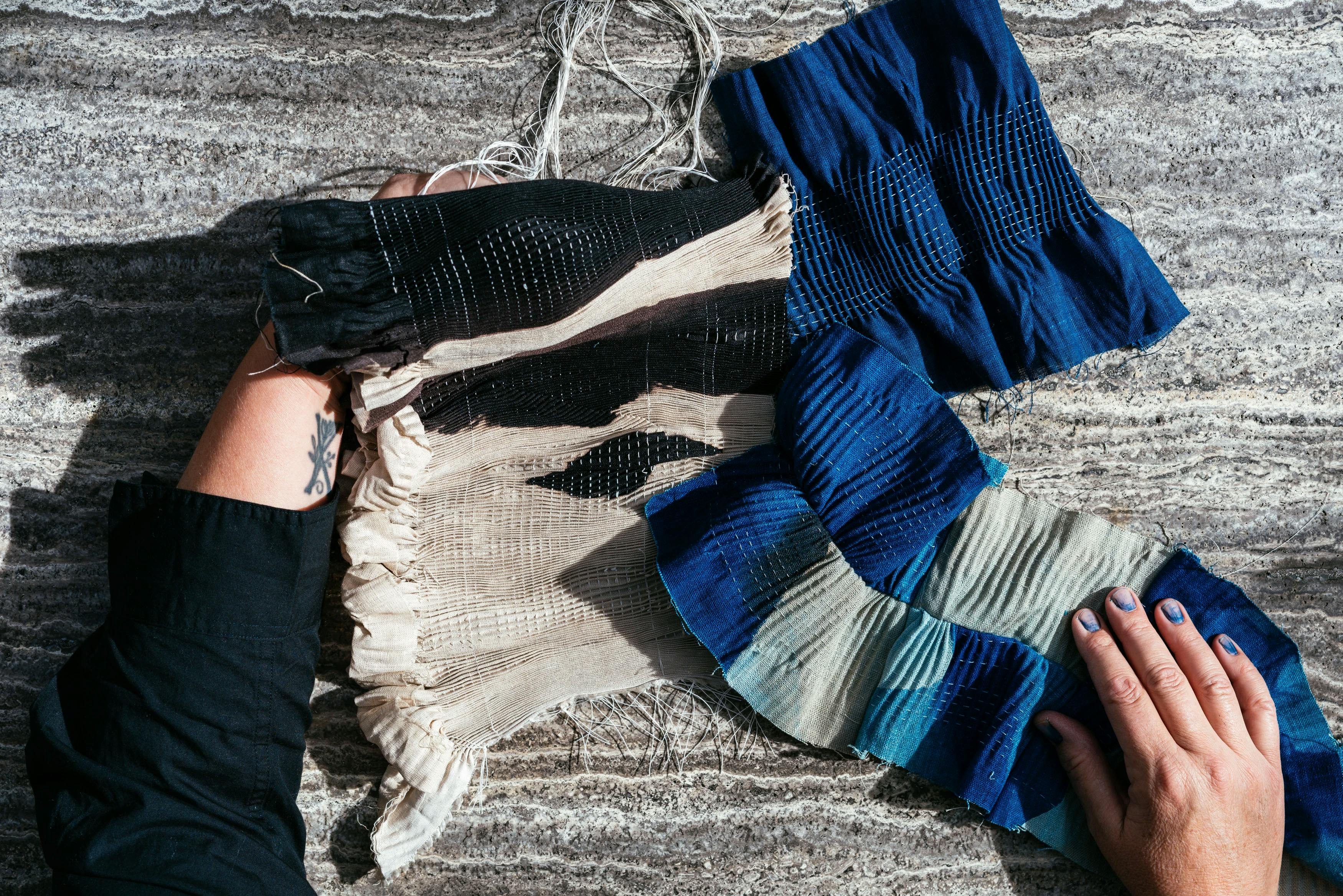 Artist Carrie Crawford holding strands of blue dyed fabric. 