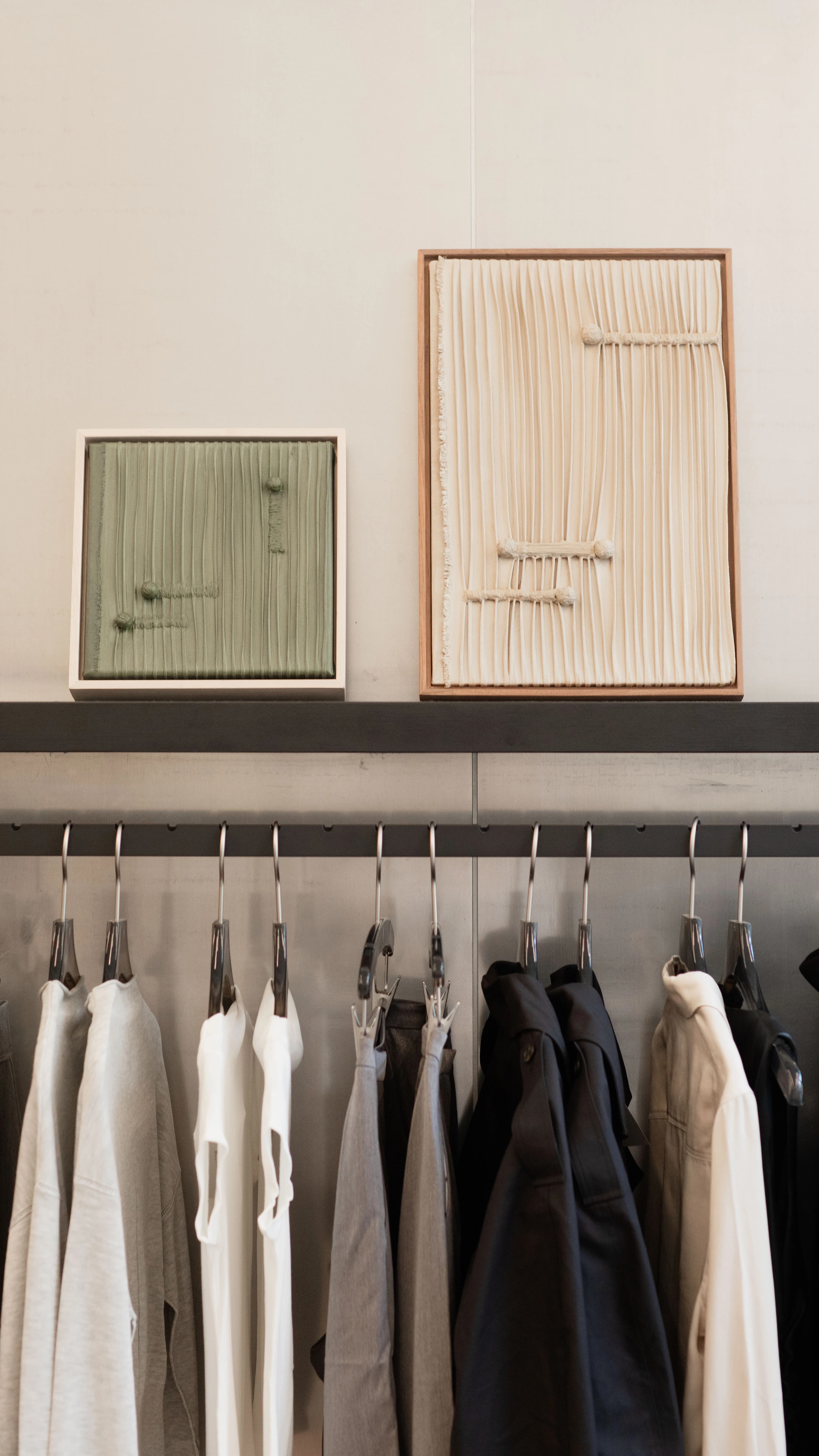 Two monochrome textile-based pieces, one green and one beige, by artist Nicole Anastas displayed on a shelf at Modern Citizen store.