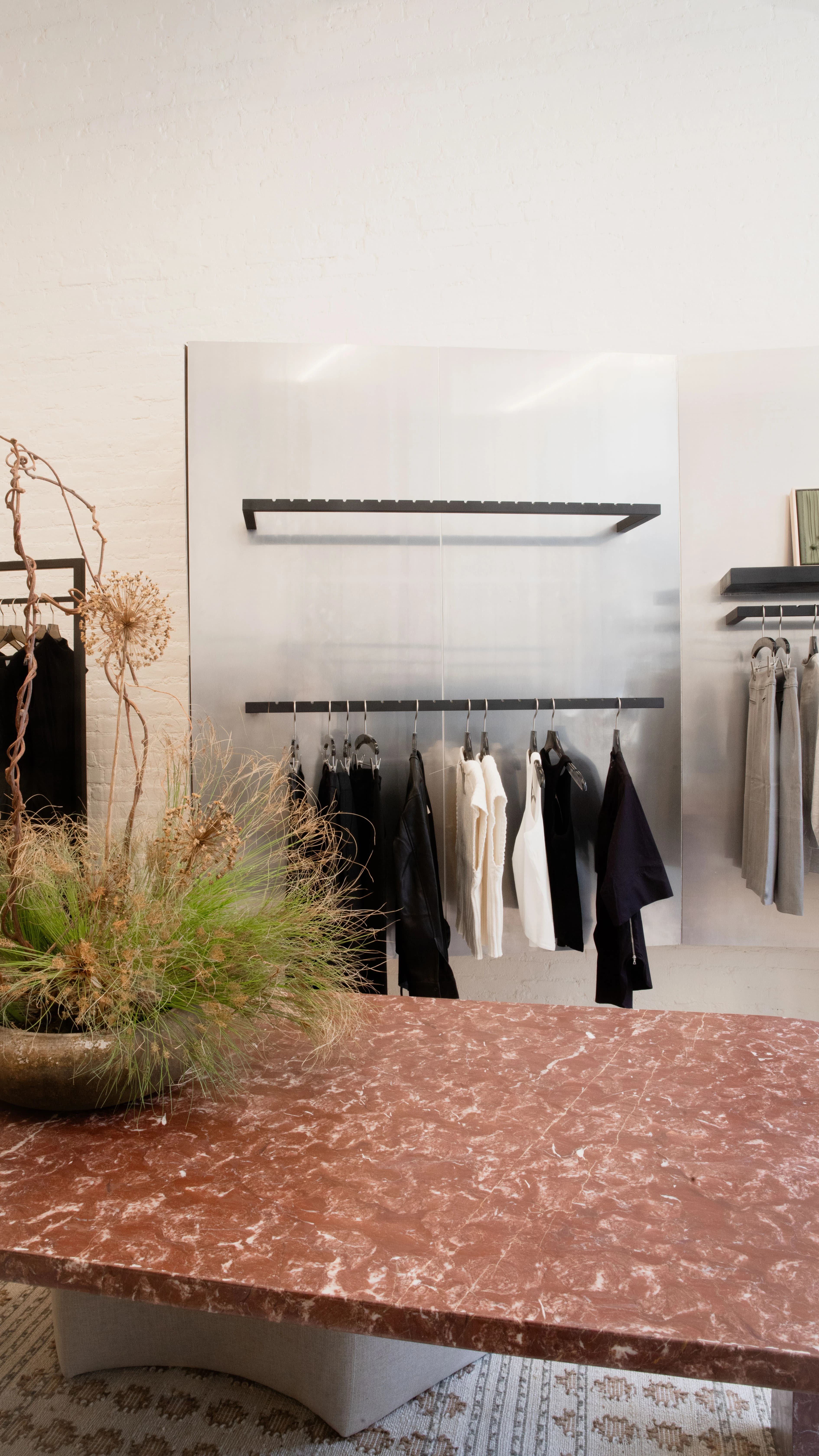 A rack of clothes next to a pink marble table at Modern Citizen's New York store.