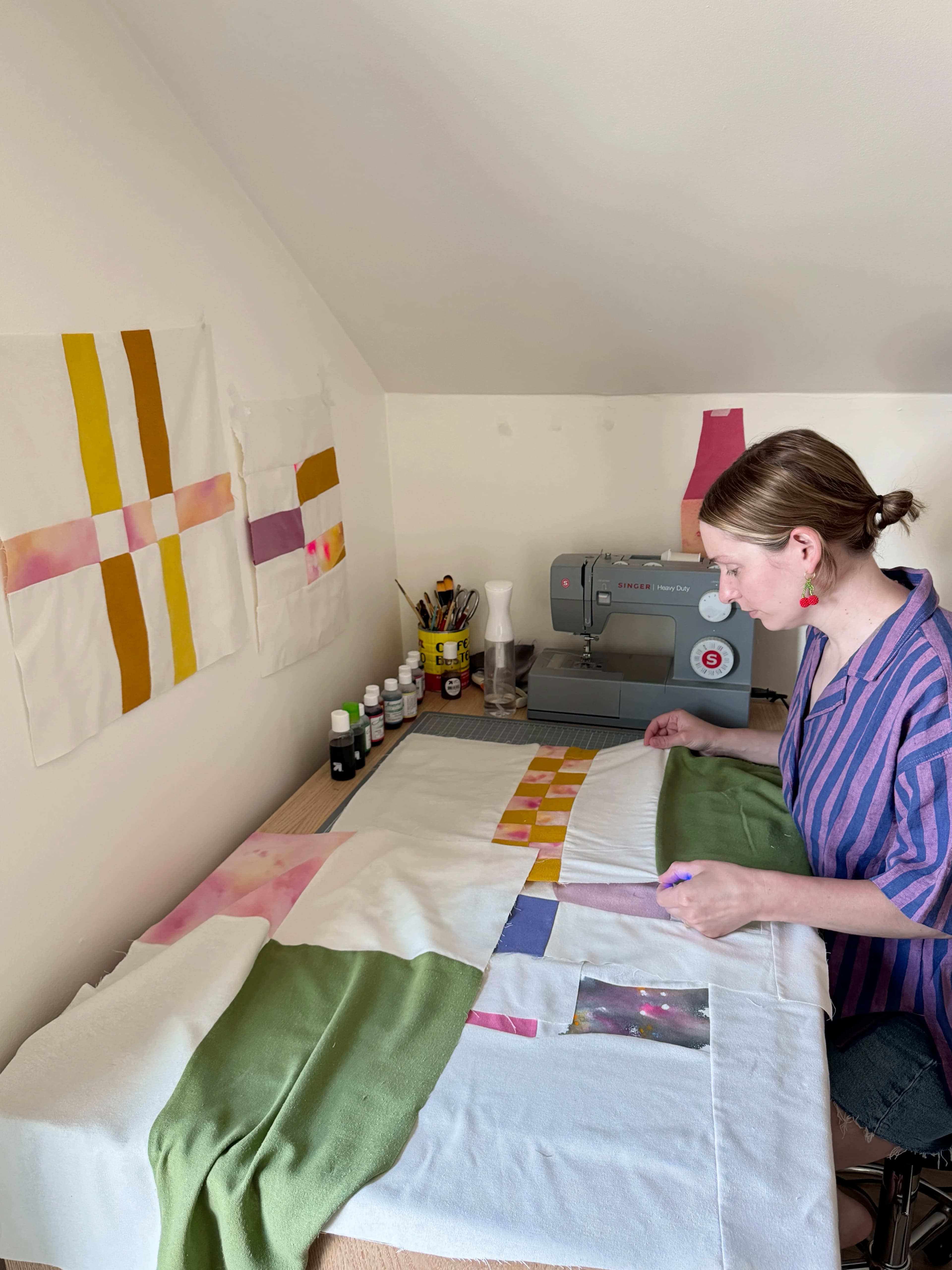 Artist Anastasia Greer layering sewn textile pieces in her studio. 