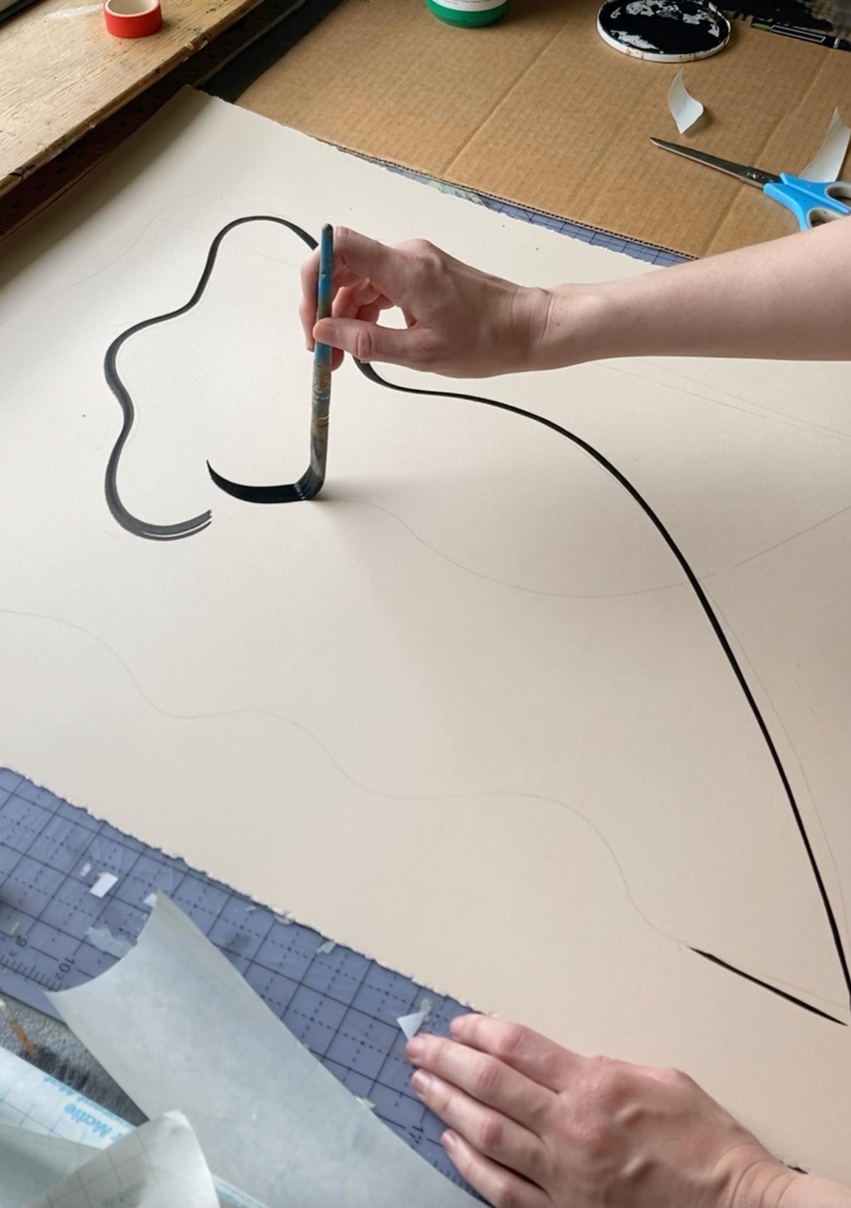 A close-up of artist Anna Koeferl painting a figurative silhouette with a thin black paintbrush.