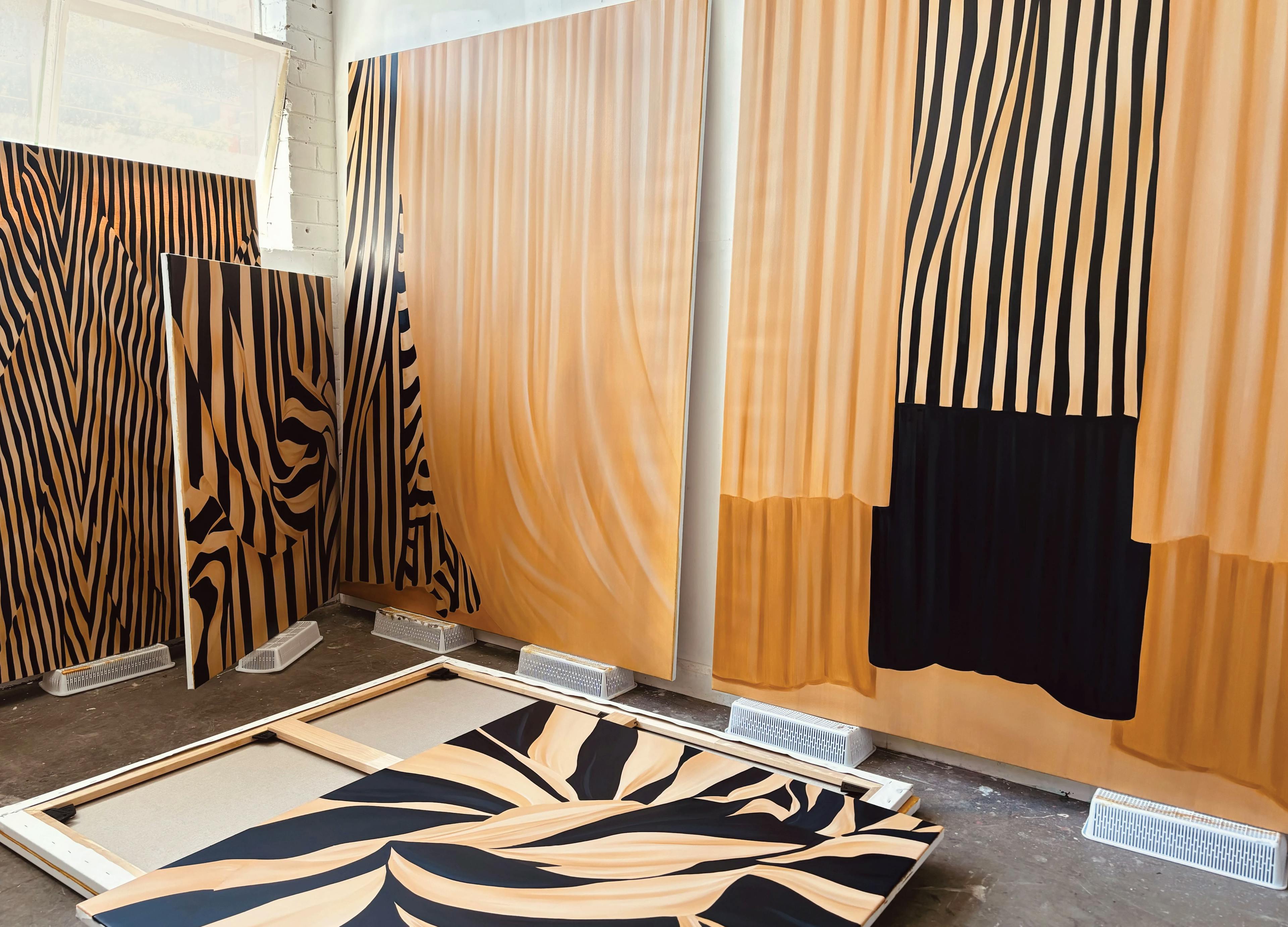 Large, beige and black striped paintings on canvas in artist Caroline Walls' studio.