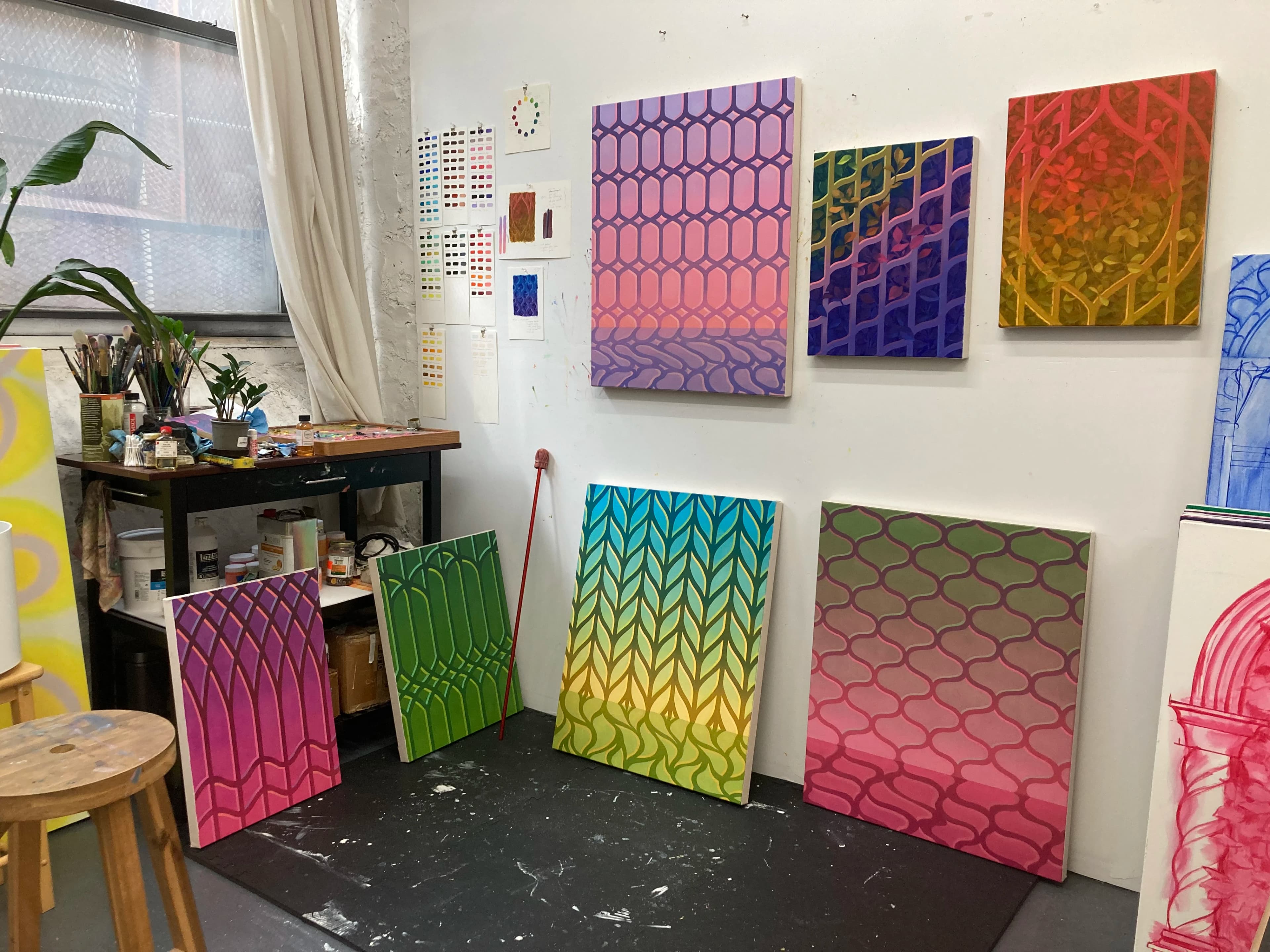 Colorful, vibrant paintings with lattice patterns by artist Lucía Rodríguez Pérez in her studio.