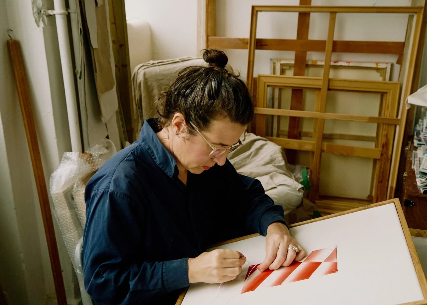 Artist Mada Vicassiau hand-sewing a textile-based work in her studio.