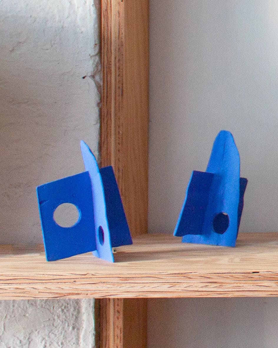 Two blue sculptures by Fitzhugh Karol on a wood shelf.