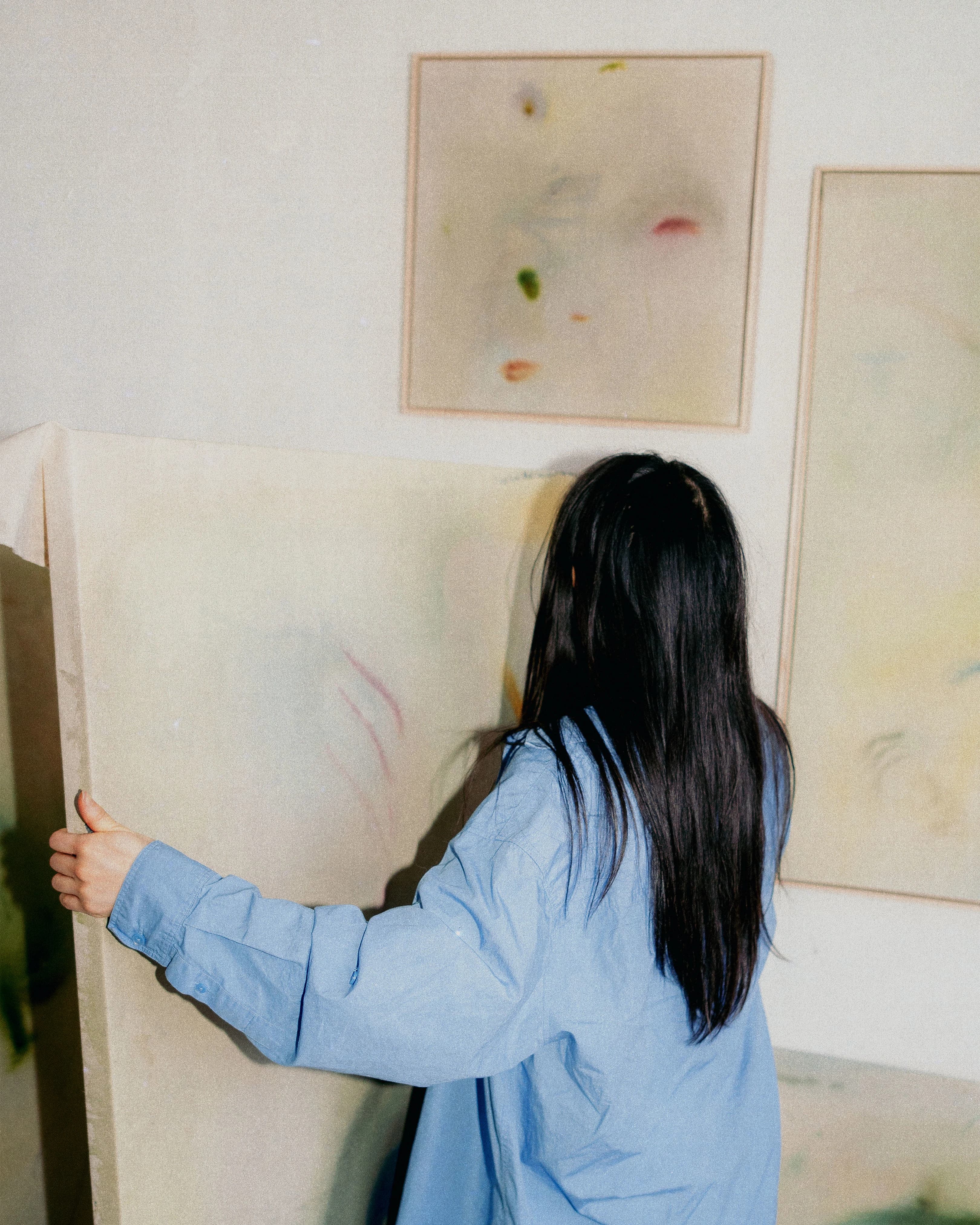 Artist Arlina Cai holding a canvas in her studio.