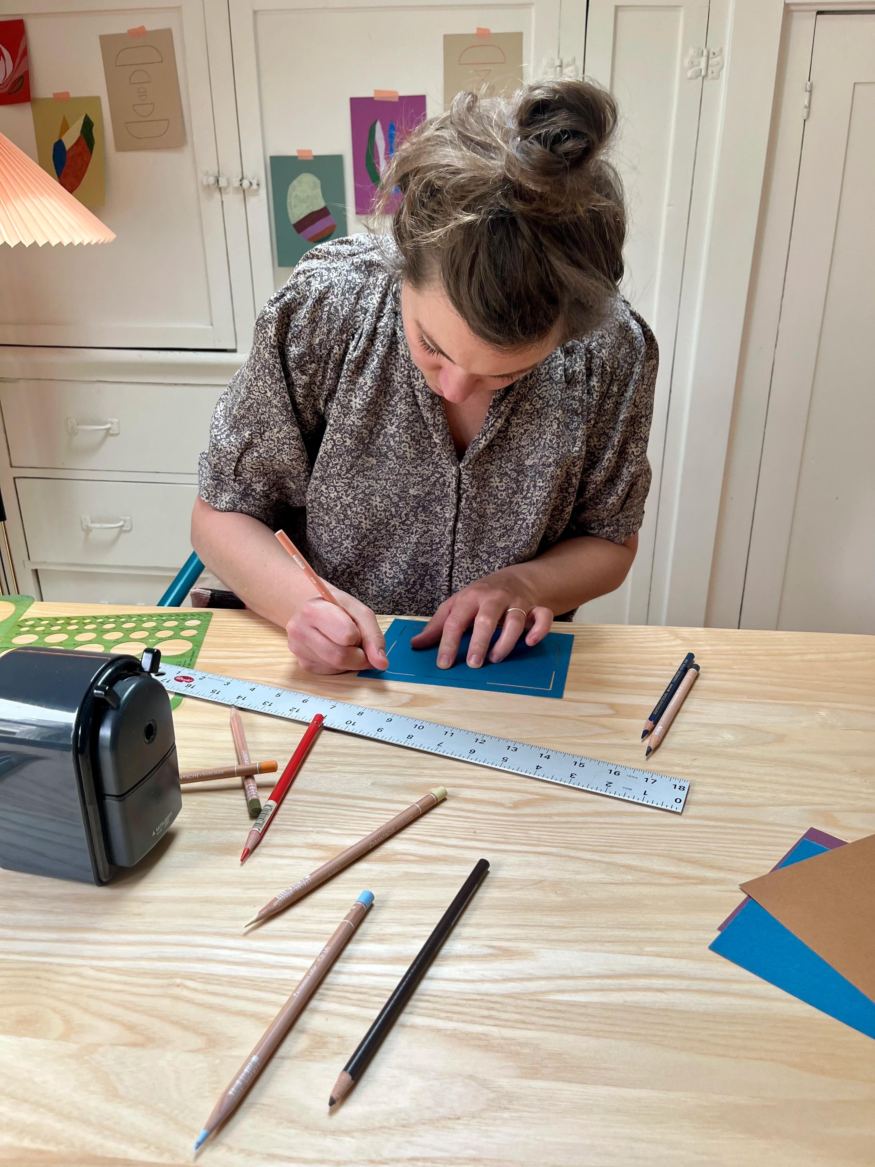 Artist Chloe Fields working on a small blue work in her studio.