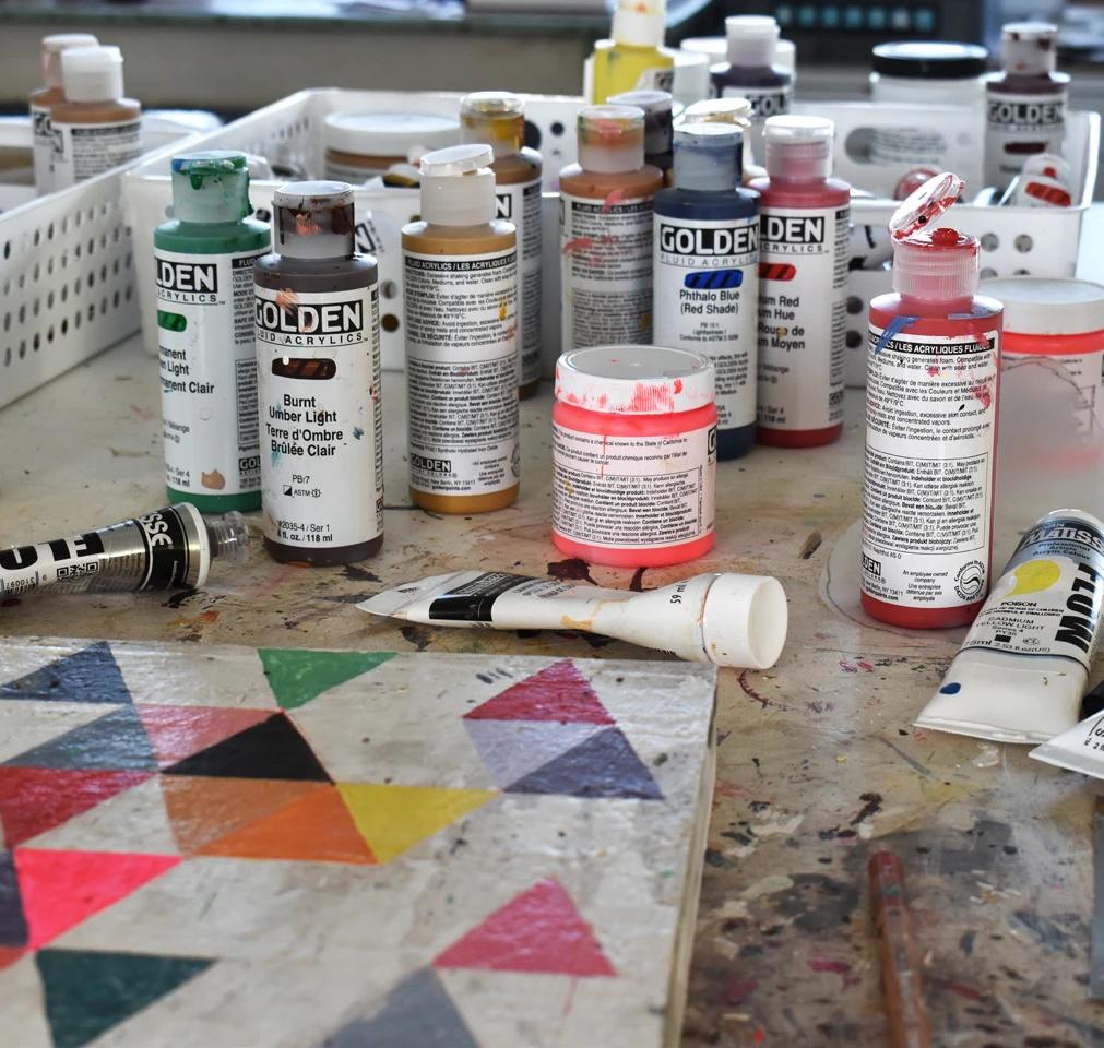 Bottles of paint next to a geometric work in artist Susan Simonini's studio.