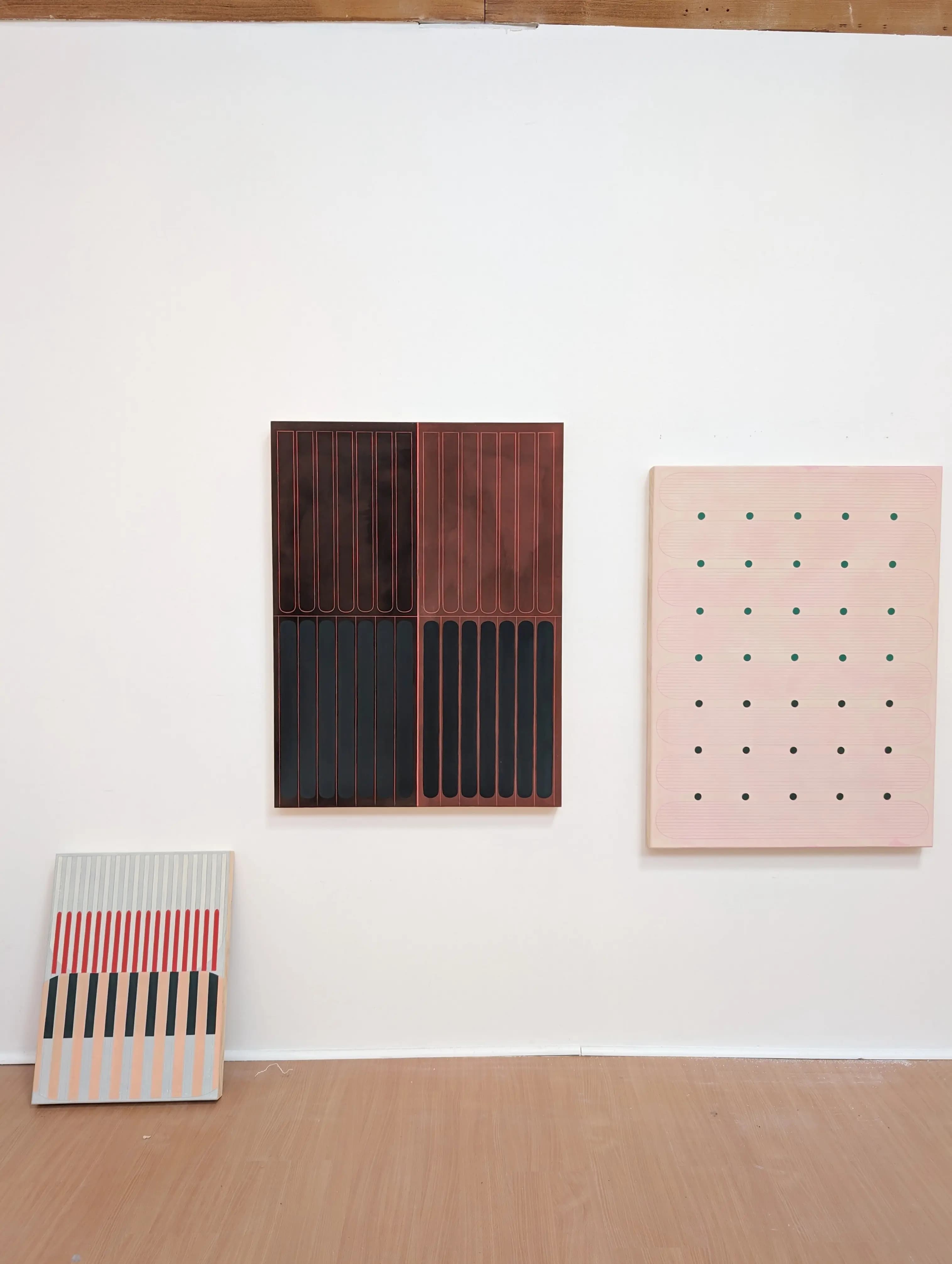 Three minimalist, geometric pink works on panel by artist Arielle Zamora in their Portland studio.